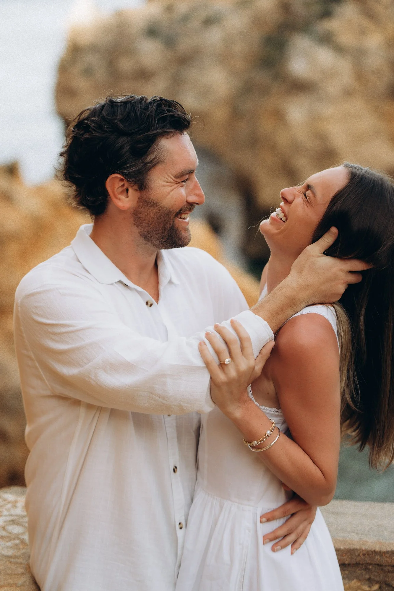 Newly engaged couple laughing together on Algarve coast, candid engagement photography Portugal