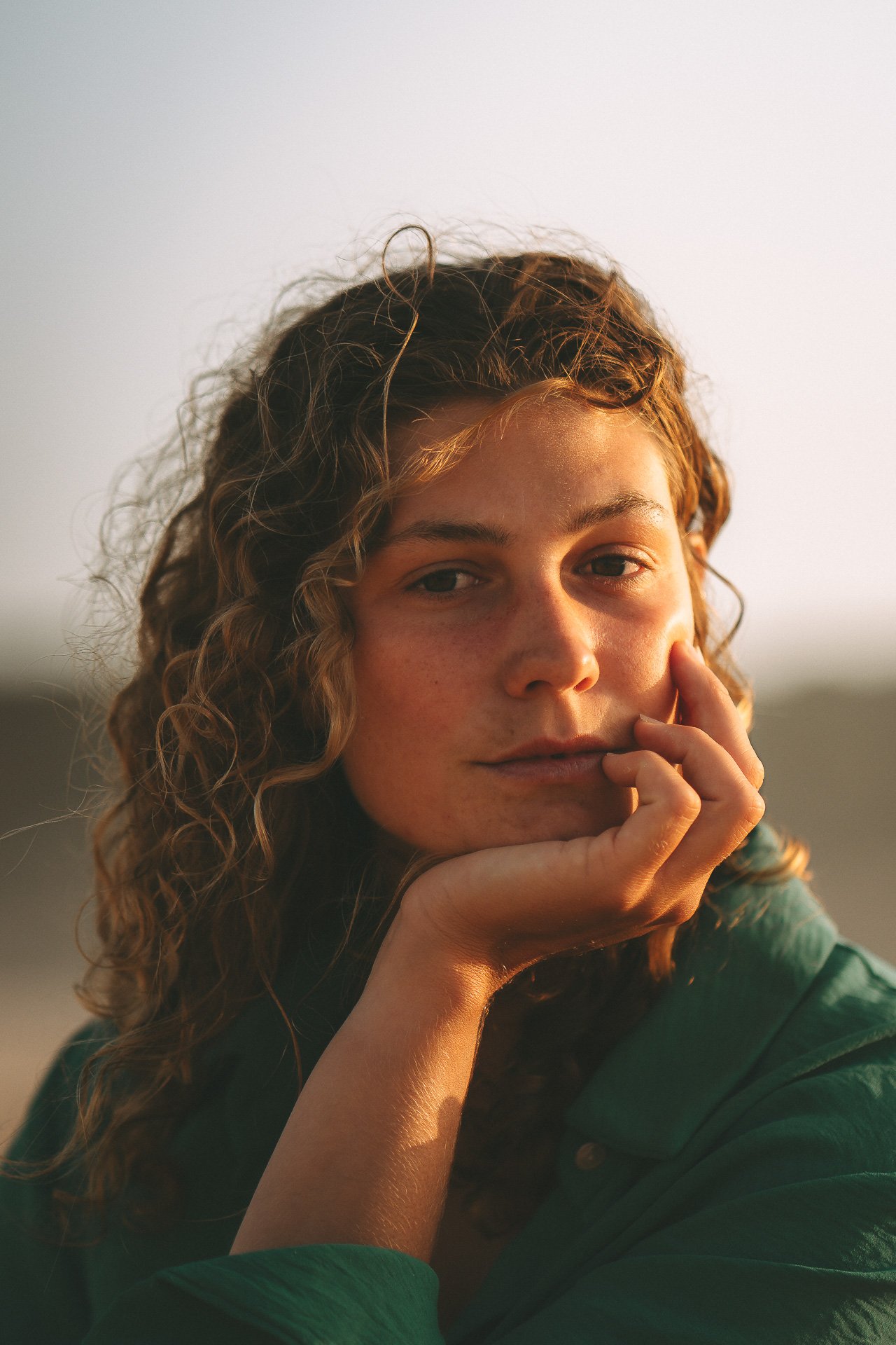 Natural portrait at Bordeira Beach, Algarve. Soft golden light, wind in the hair and a quiet, introspective mood along the Atlantic coast.