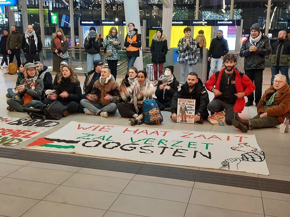 Protesters inside Utrecht Central Station hold Palestinian flags and signs calling for justice and peace. Photo by Ciell / Wikimedia Commons