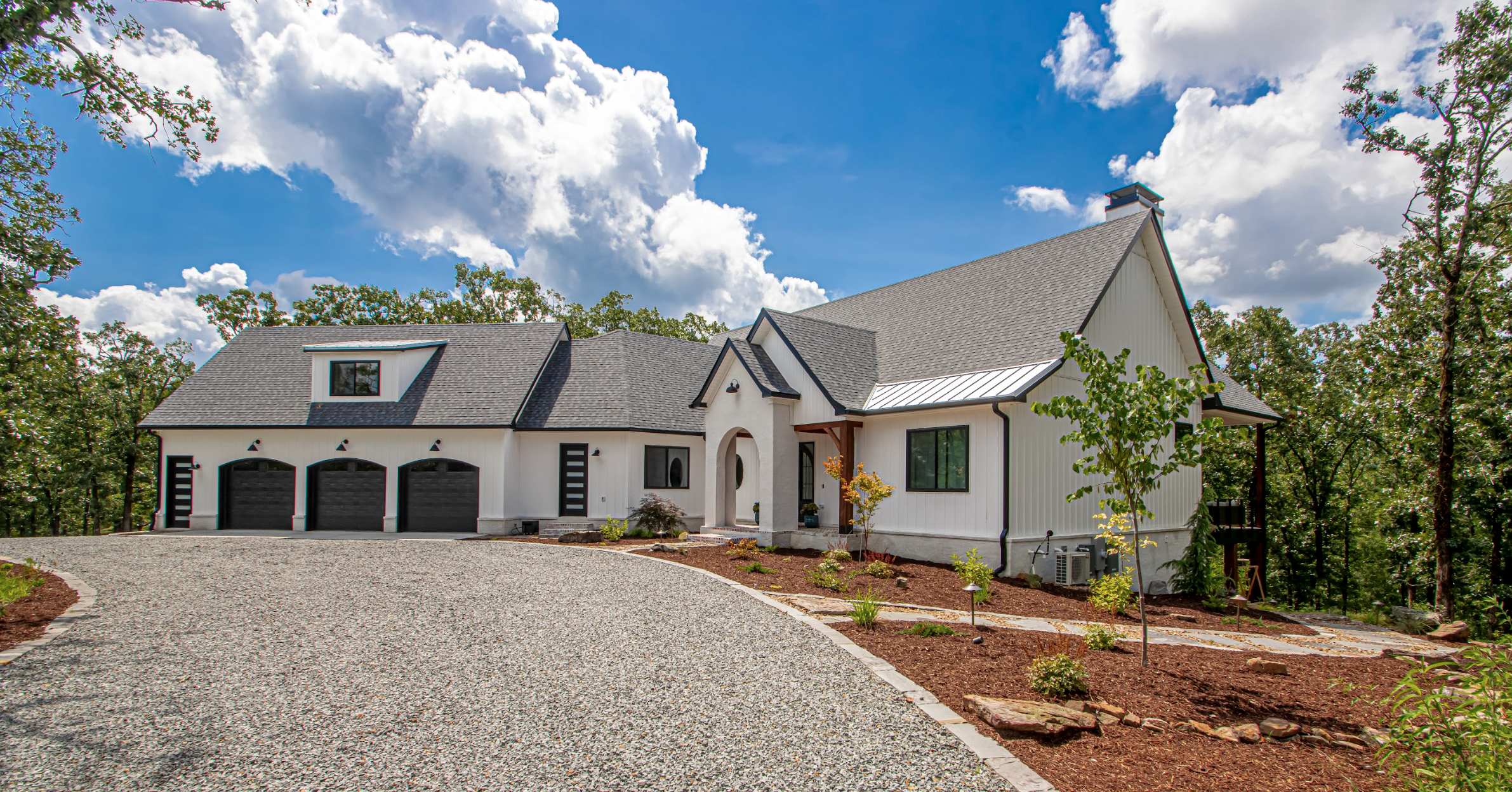 Modern white house with black roof and trim, front porch with archway, landscaped yard, and curved walkway.