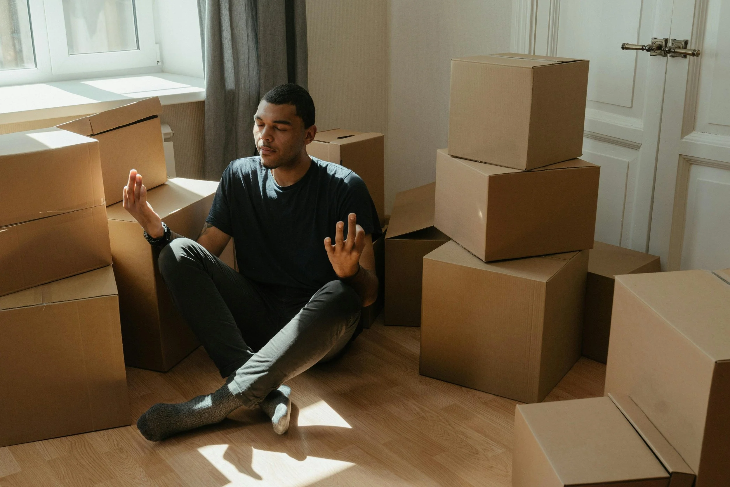 Man meditating peacefully among organized boxes