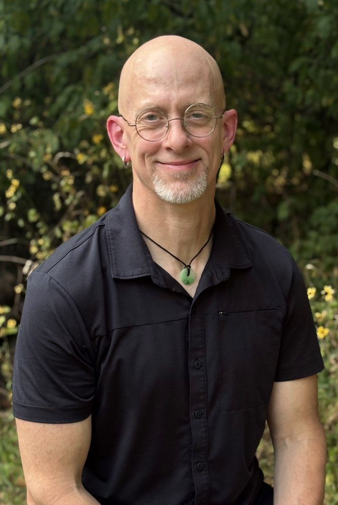 Arkansas therapist for men in black shirt. He wears round-rimmed glasses and a jade pendant.