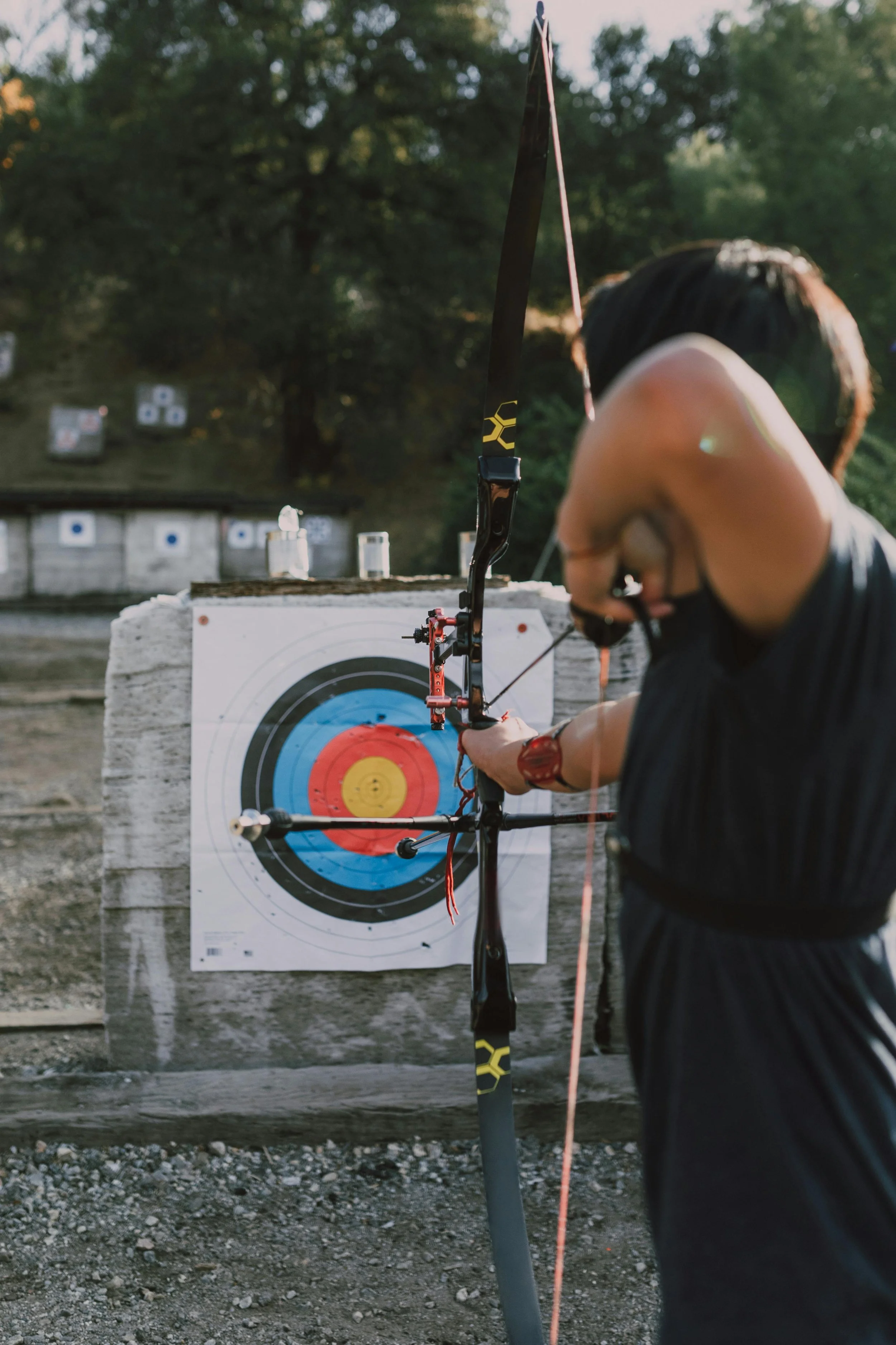 Man practicing archery draws back an arrow, aiming at a bullseye target. Photo by RDNE Stock Project.