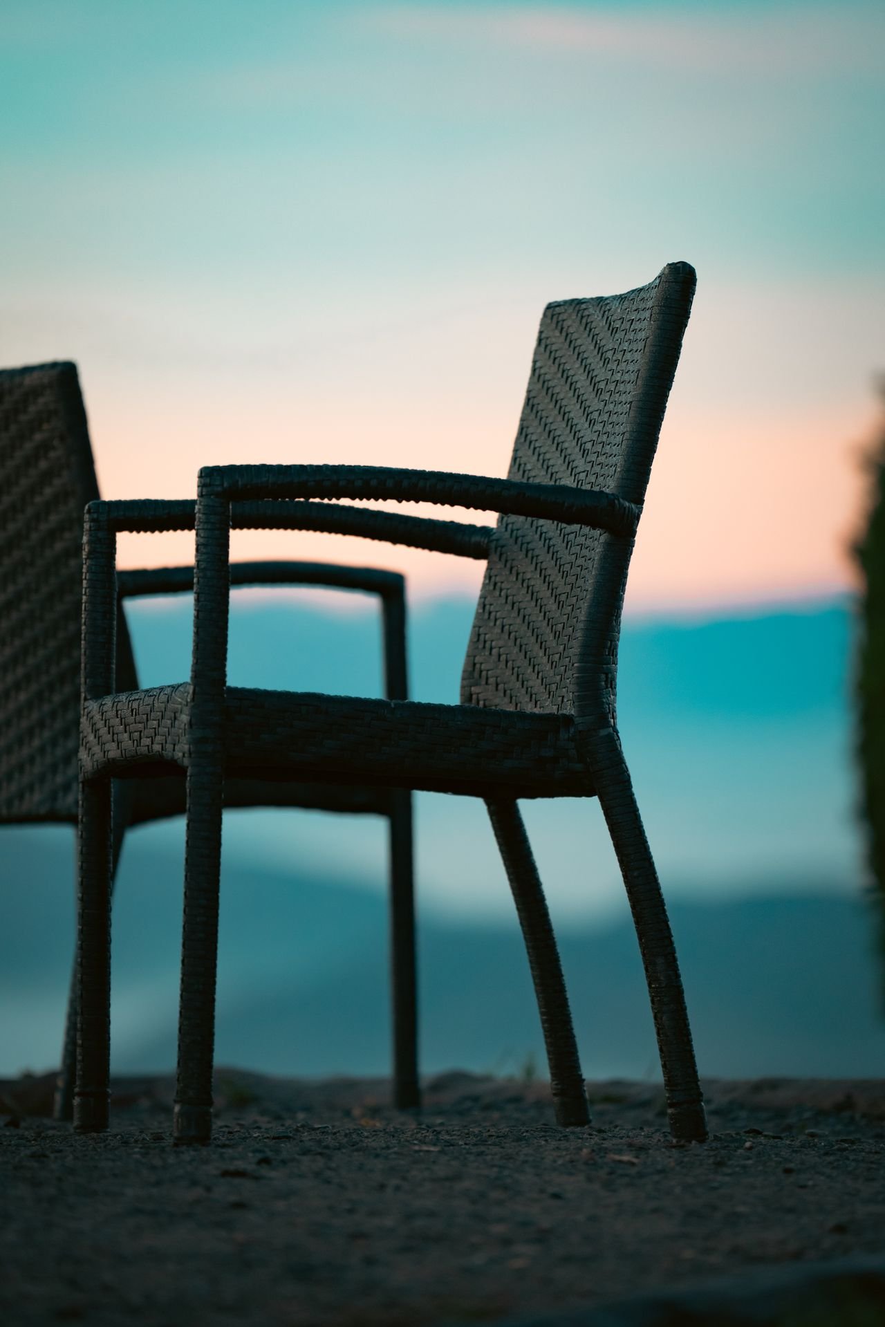 Two chairs face opposite each other against blue mountains and a soft orange sunset. Sometimes relationship problems feel like you and the other person can't face each other and see eye-to-eye.