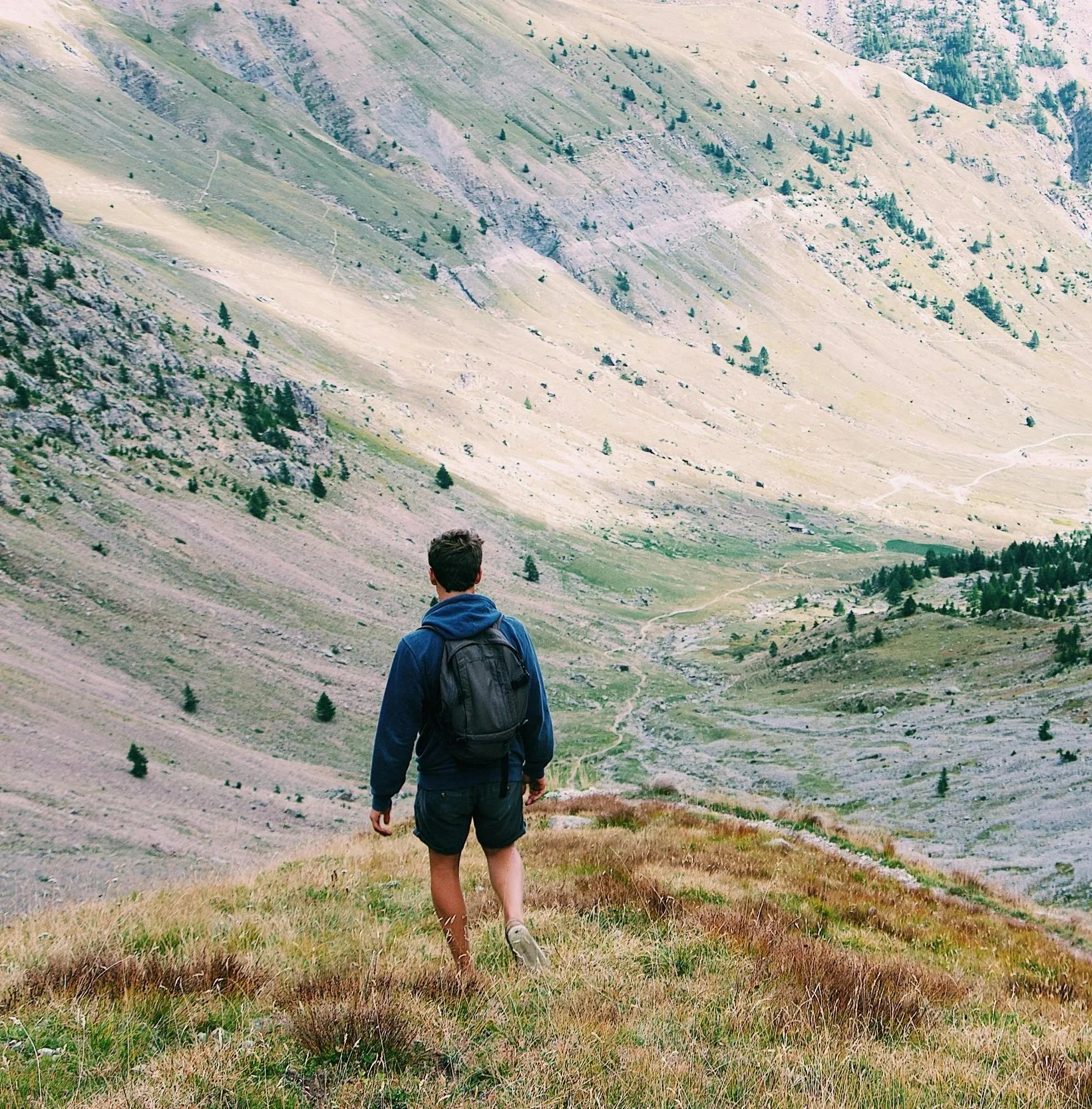 Man in blue hoodie walks steadily along mountain trail
