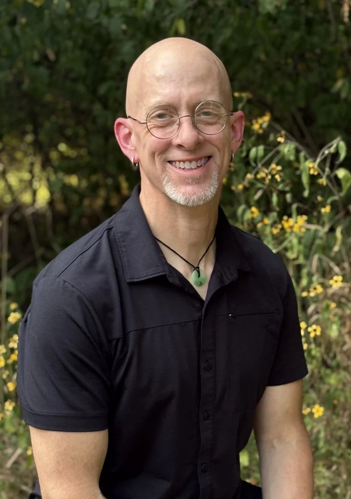 Arkansas therapist for men in black shirt. He wears round-rimmed glasses and a jade pendant.