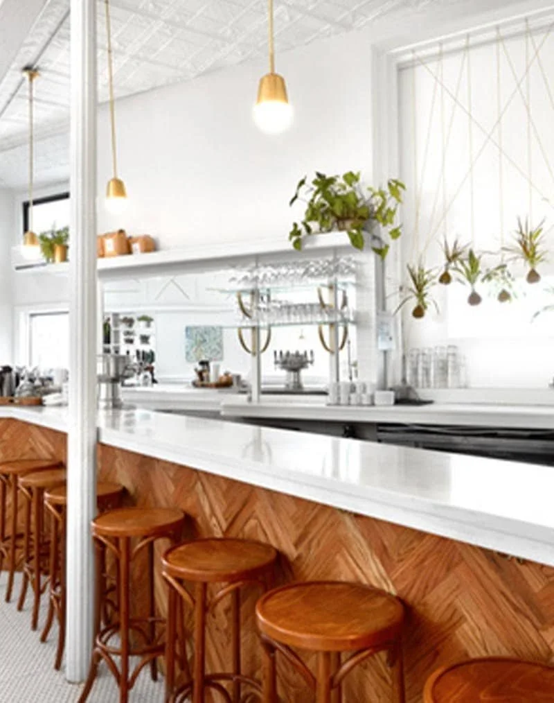 Minimalist bar with wooden stools, marble counters, and greenery accents | The Morris Project