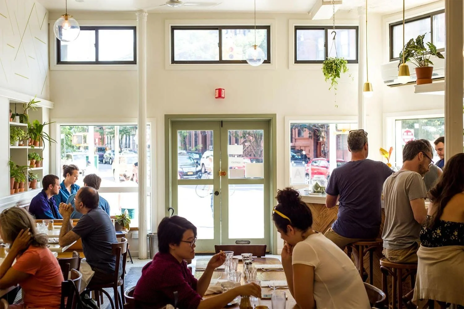 Vibrant café with natural light, communal seating, and greenery accents | The Morris Project