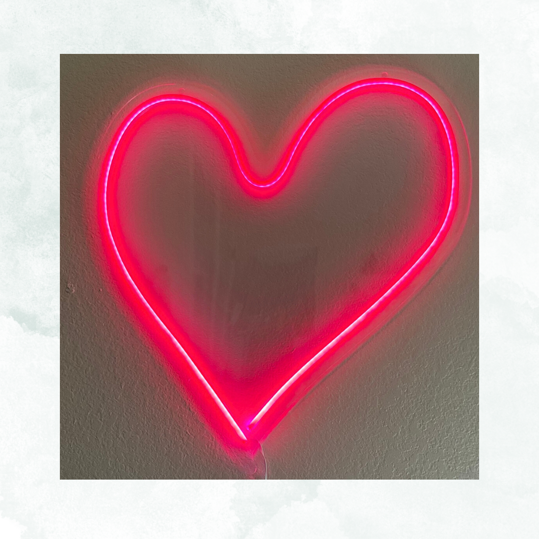 Neon pink heart outline mounted on a wall.
