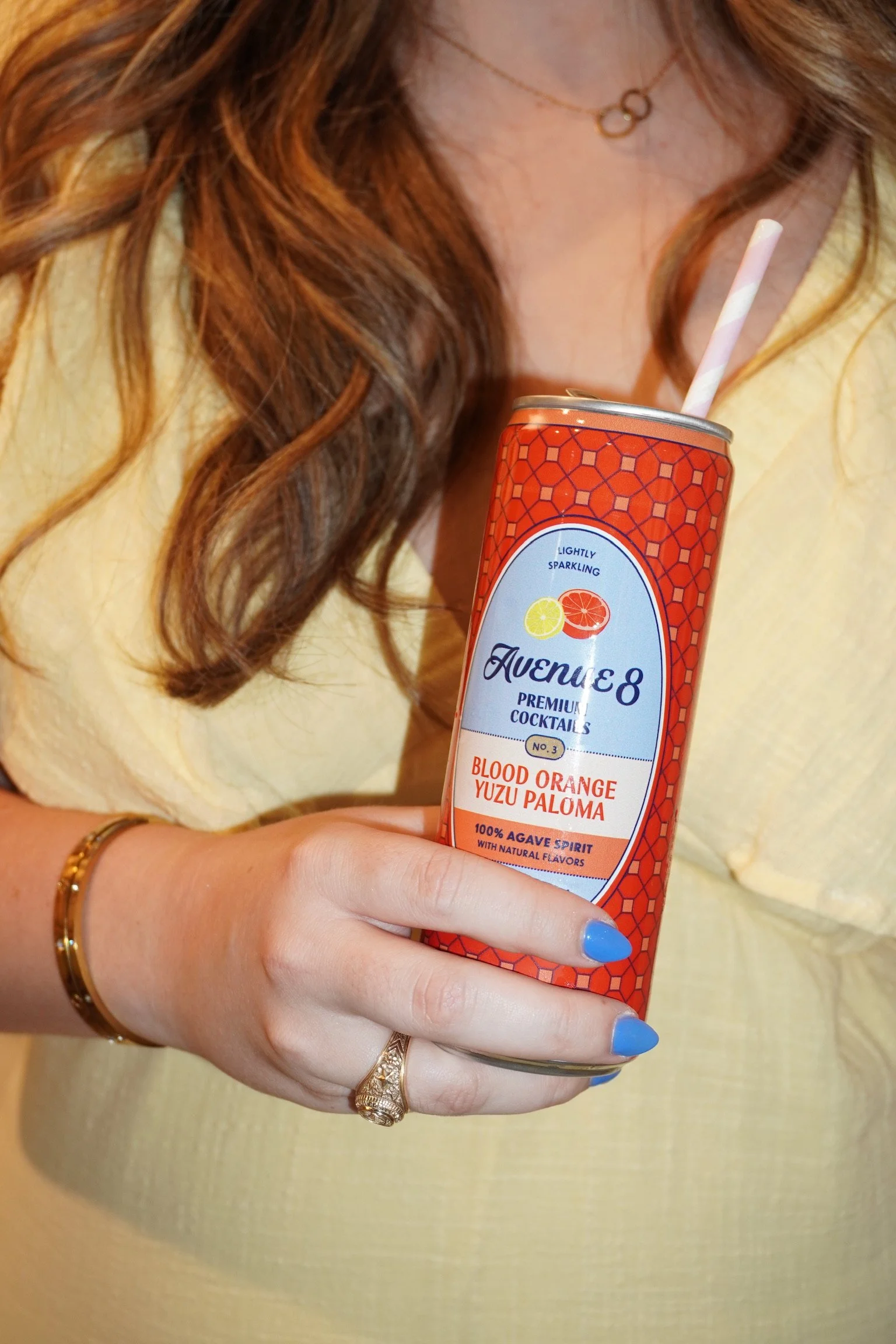 Girl's hand holding avenue 8 blood orange yuzu paloma.
