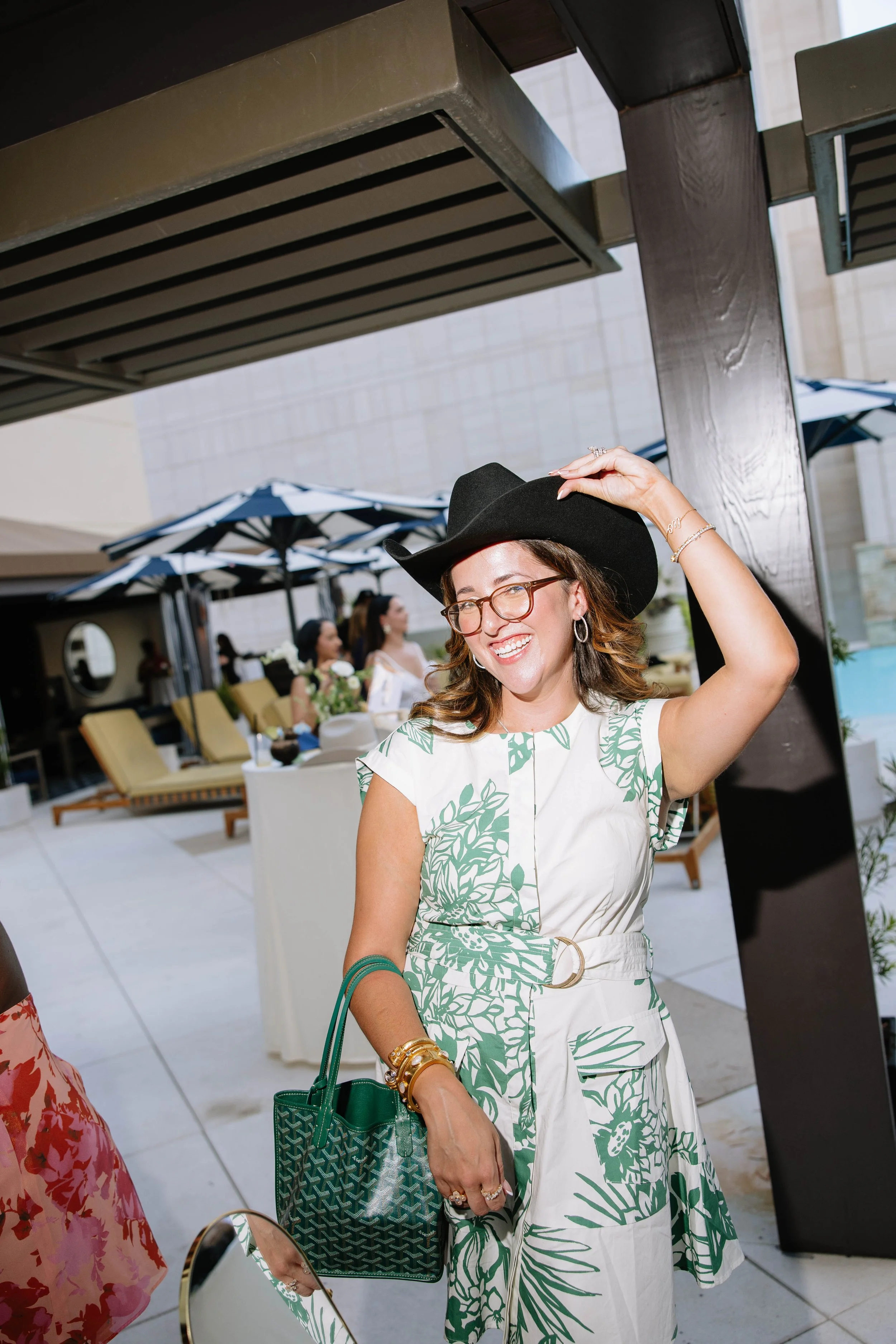 Woman wearing a cute cowboy hat with a white and green dress and green stylish handbag.