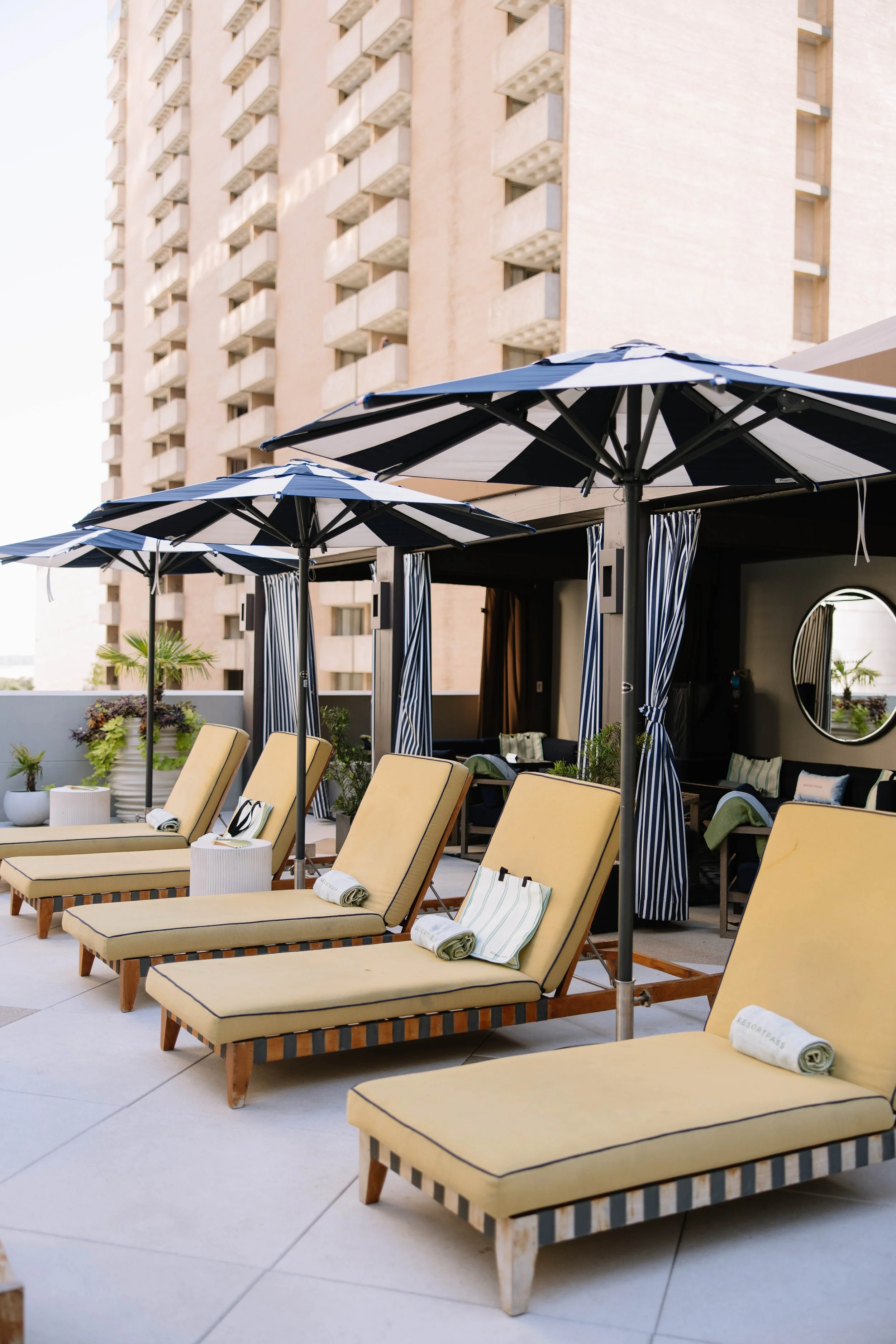 Resort Pool Lounge chairs with towels and umbrellas on a rooftop pool.