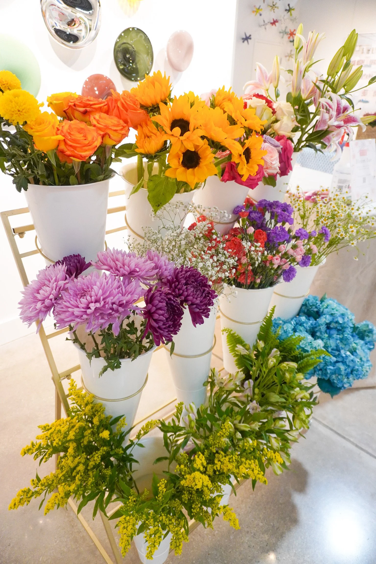 Flower stand with sunflowers, roses, greenery.