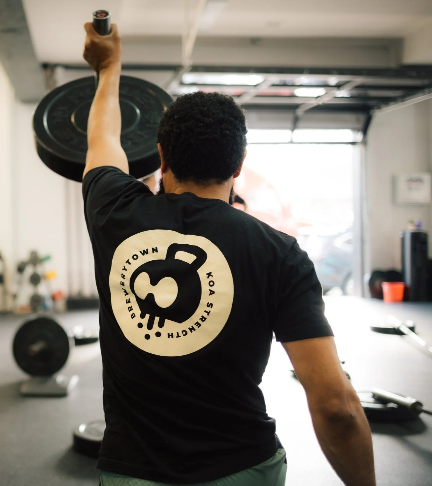 A person lifting a weight plate during a workout in a gym.