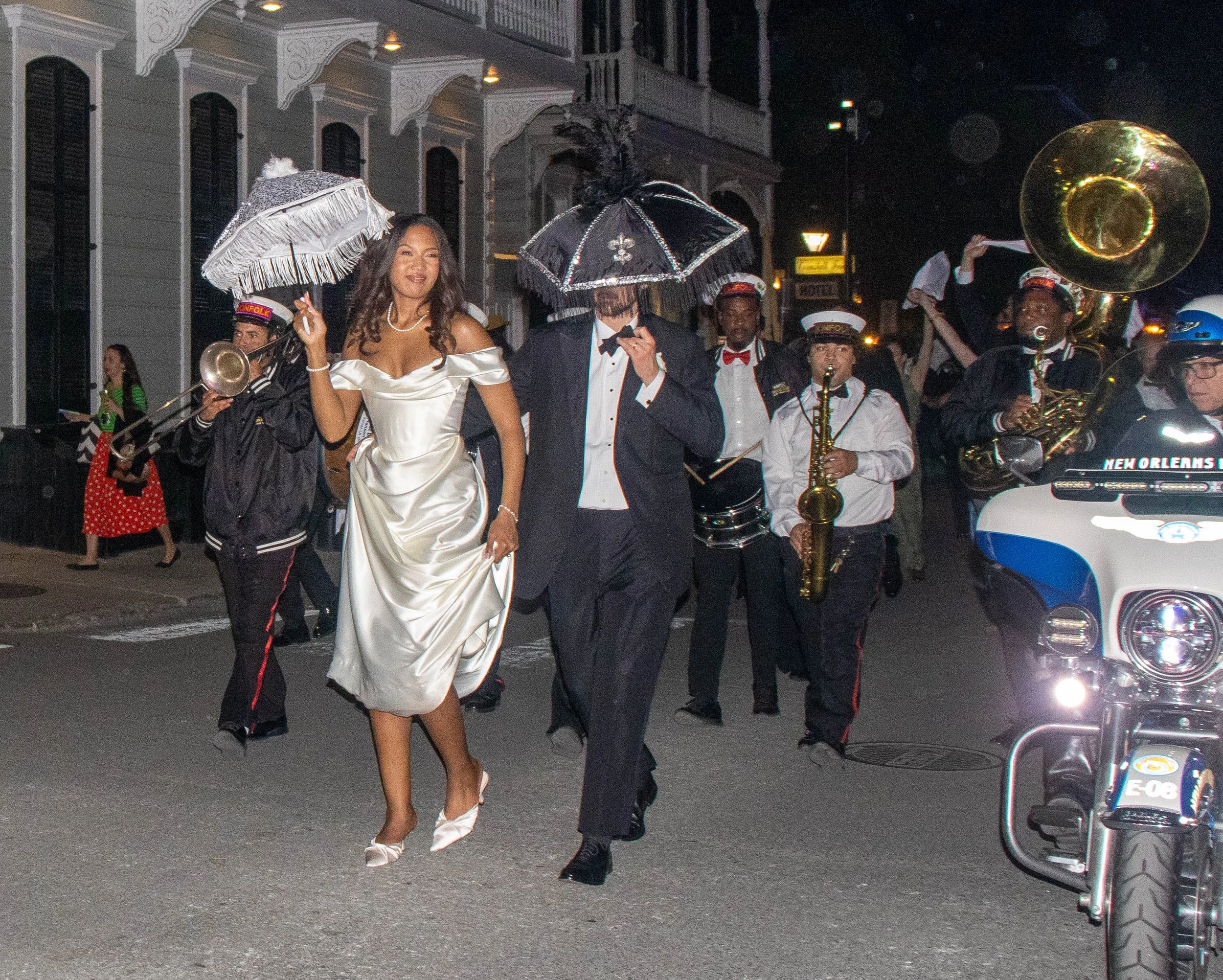 A bride and groom lead the Second Line parade, with a brass band playing behind them, down Royal Street in New Orleans on Friday night, March 13, 2026. The Second Line parade is a celebratory tradition, such as weddings, in New Orleans.
