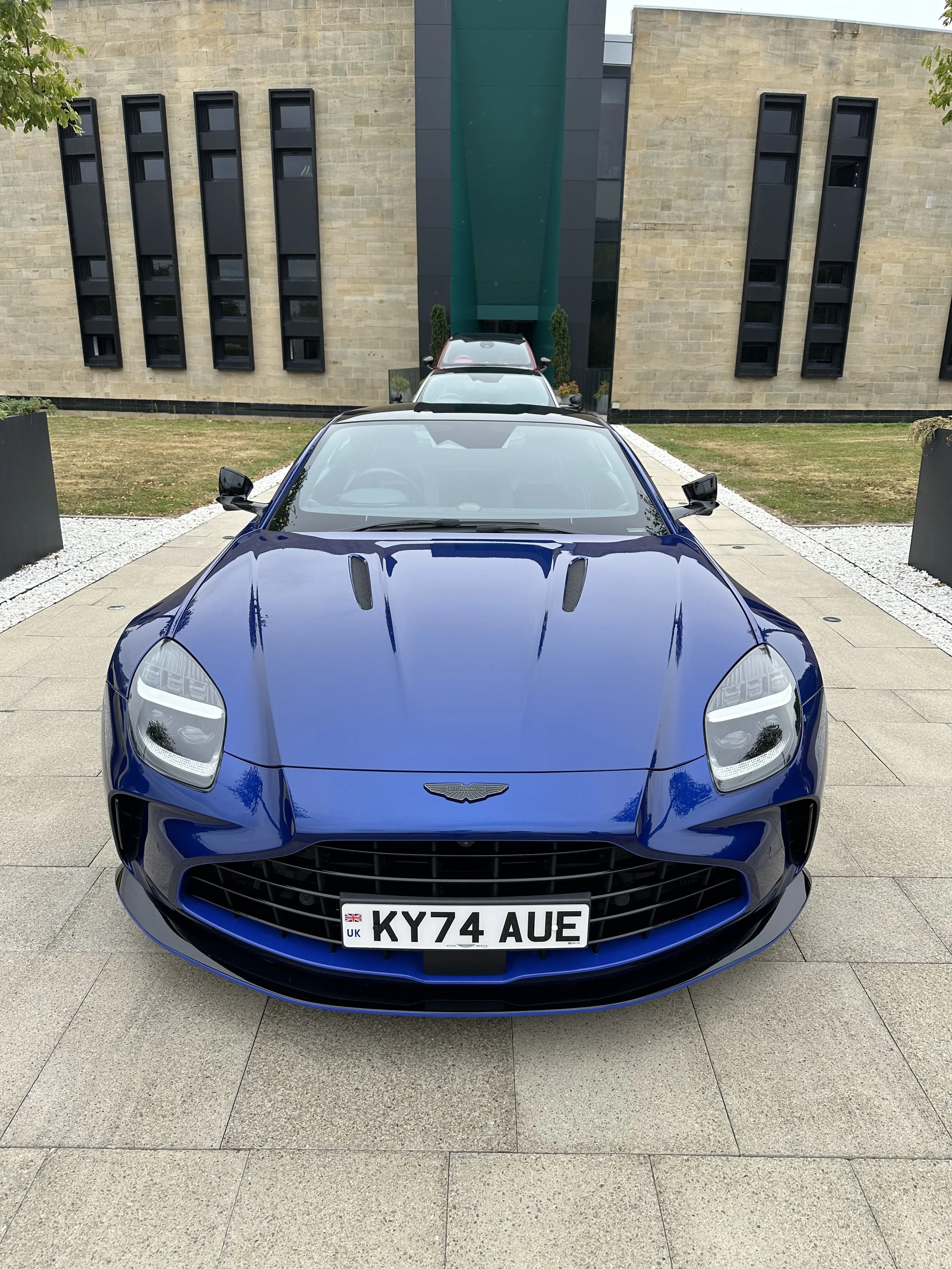 Aston Martin vehicles aligned outside the Gaydon factory, reflecting the brand’s disciplined engineering environment