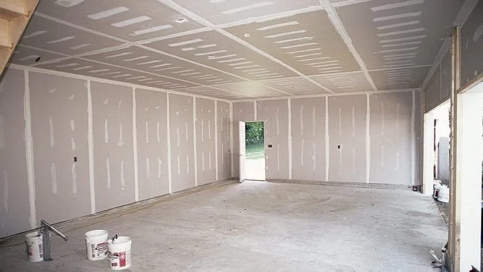 Interior new construction garage with complete drywall installation, professional taping, and initial mudding by a licensed Moreno Valley contractor.