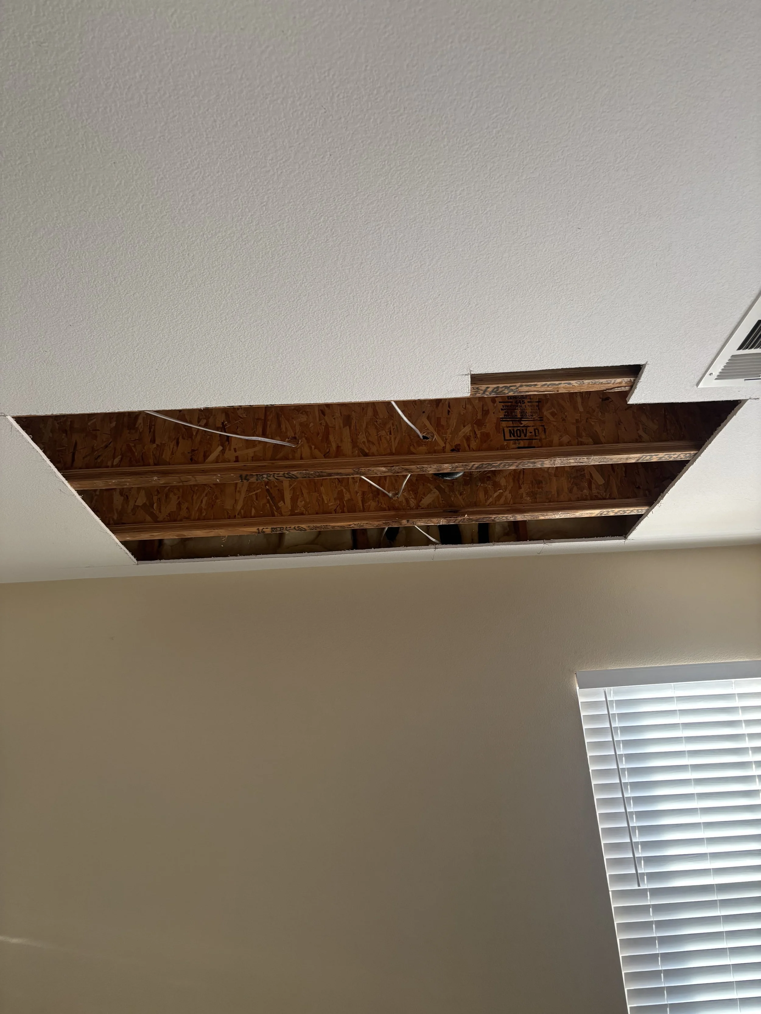 Residential ceiling water damage repair showing exposed wood engineered joists and electrical wiring before seamless drywall patch and texture restoration.