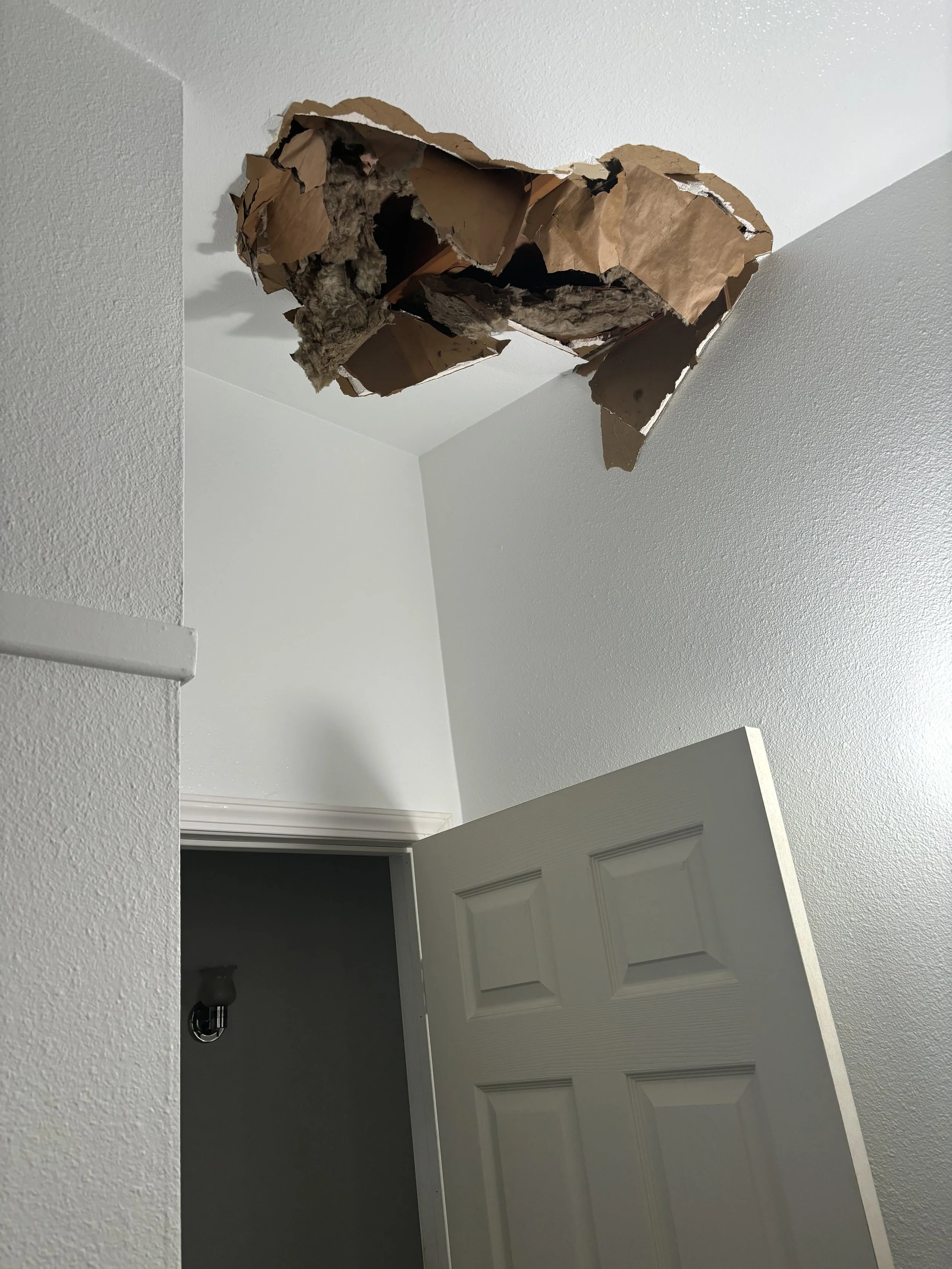 Damage to the drywall on the ceiling showing torn drywall and insulation in a home in need of a drywall repair in Corona, CA.