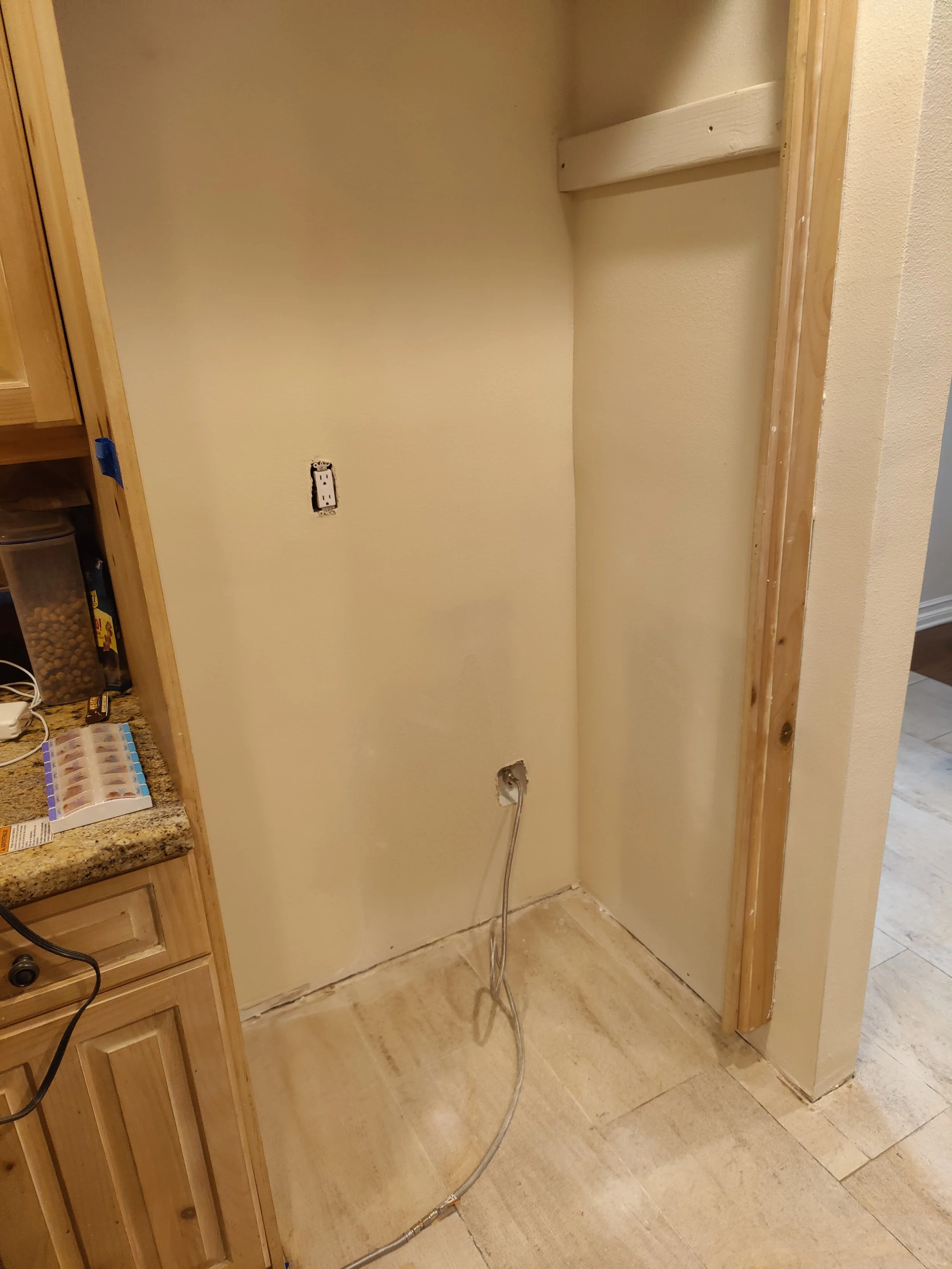 Empty kitchen nook or laundry area with electrical wiring and wall outlets visible, and partially finished walls and flooring.
