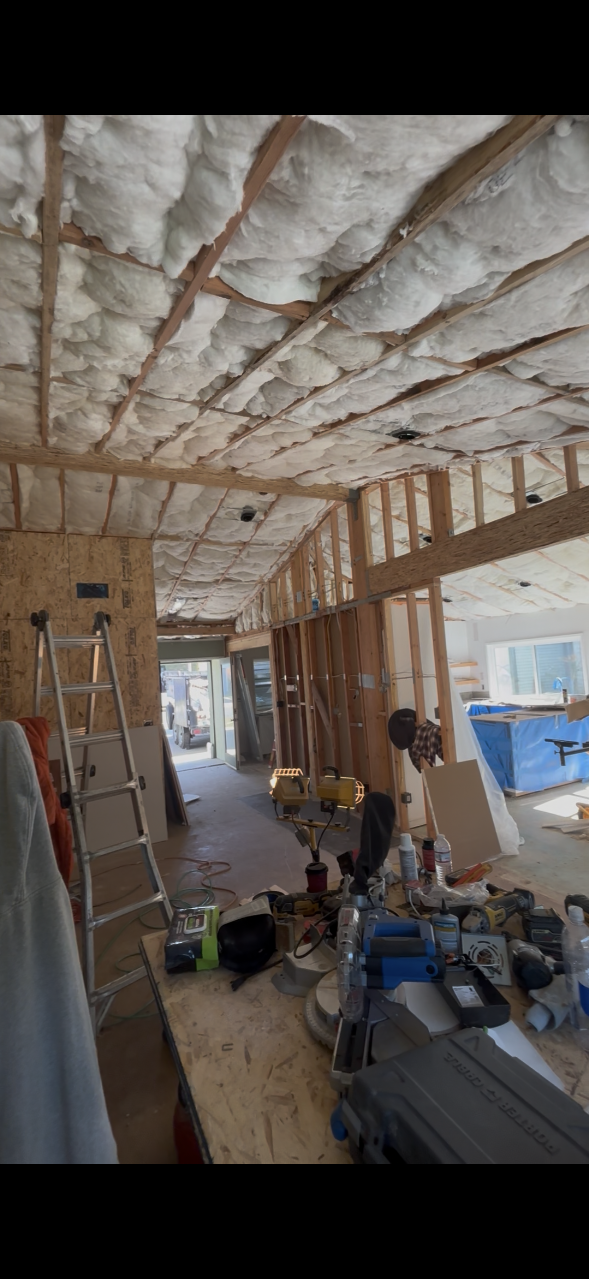 Active renovation site showing vaulted ceiling insulation and exposed wood framing prior to drywall hanging for a new home addition in Moreno Valley.
