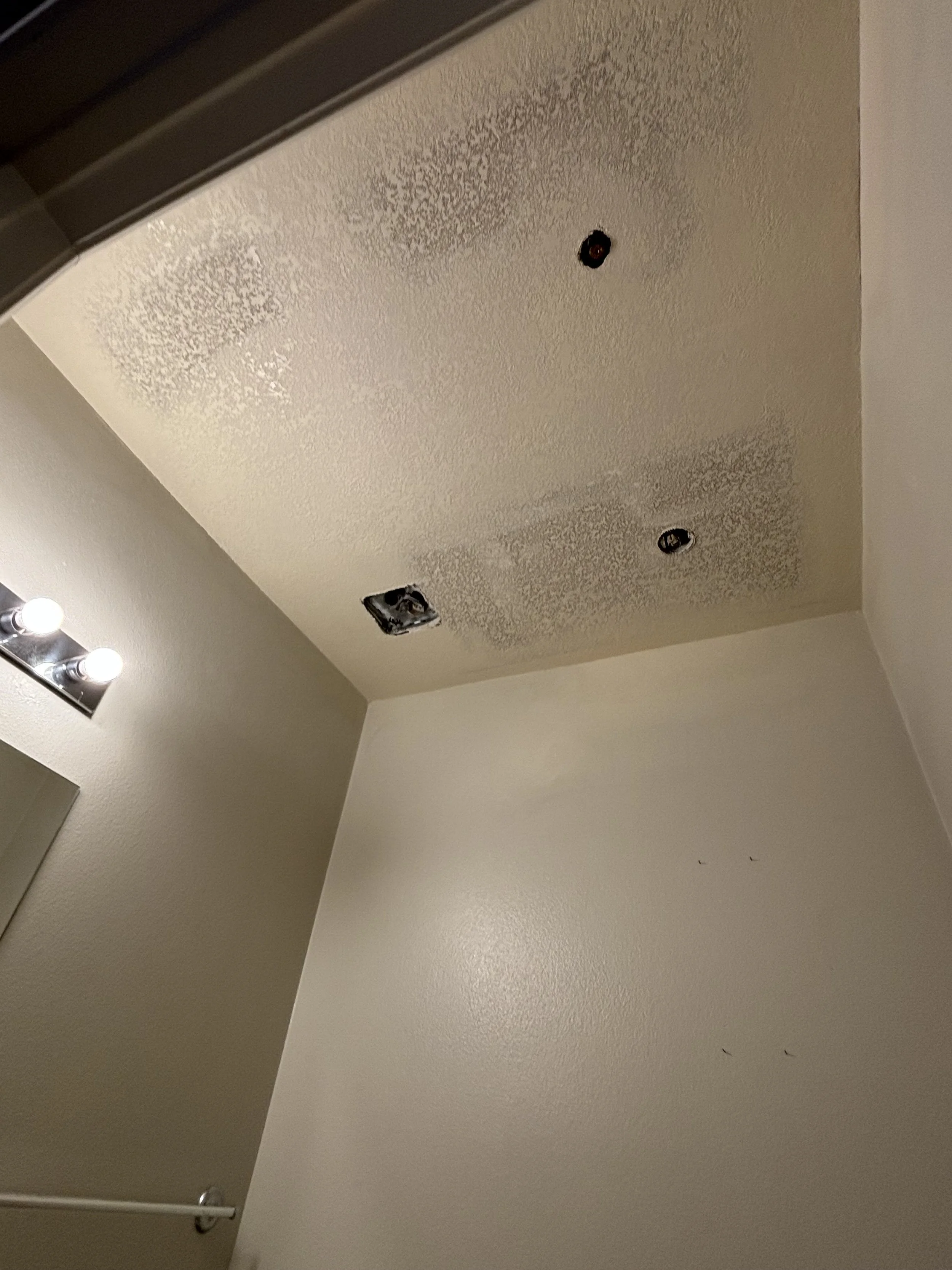 Ceiling with unfinished or damaged drywall, holes for light fixtures, and residue from construction or renovation work.