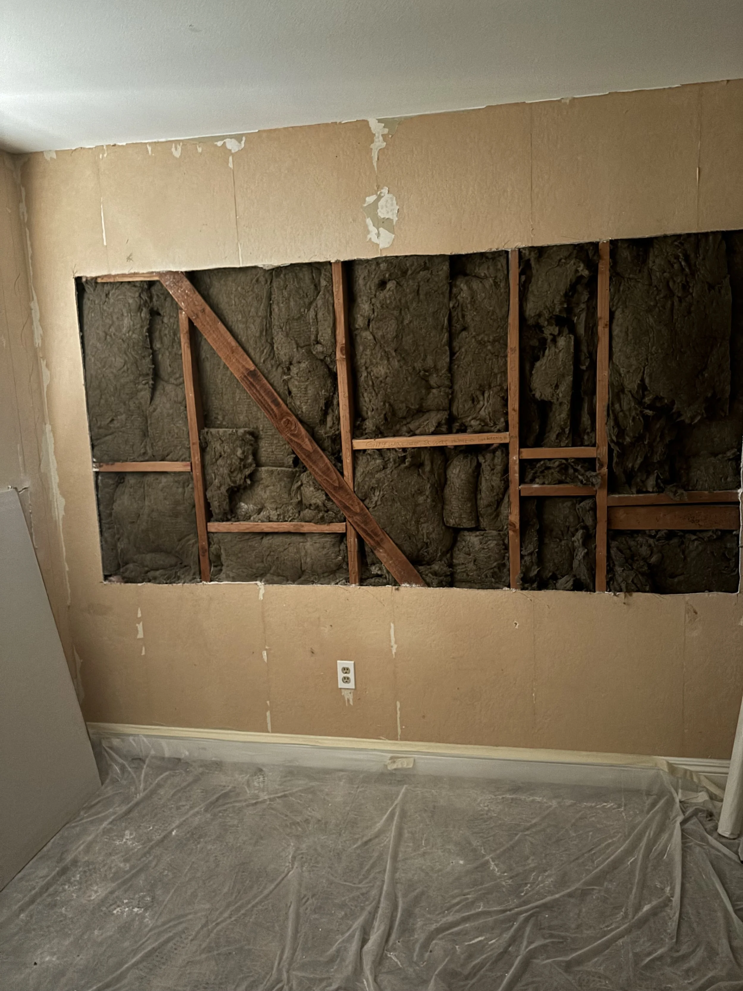 A drywall professional opened up a wall and installed insulation into the open wall cavity. Preparing the area for a skim coat and new texture. 