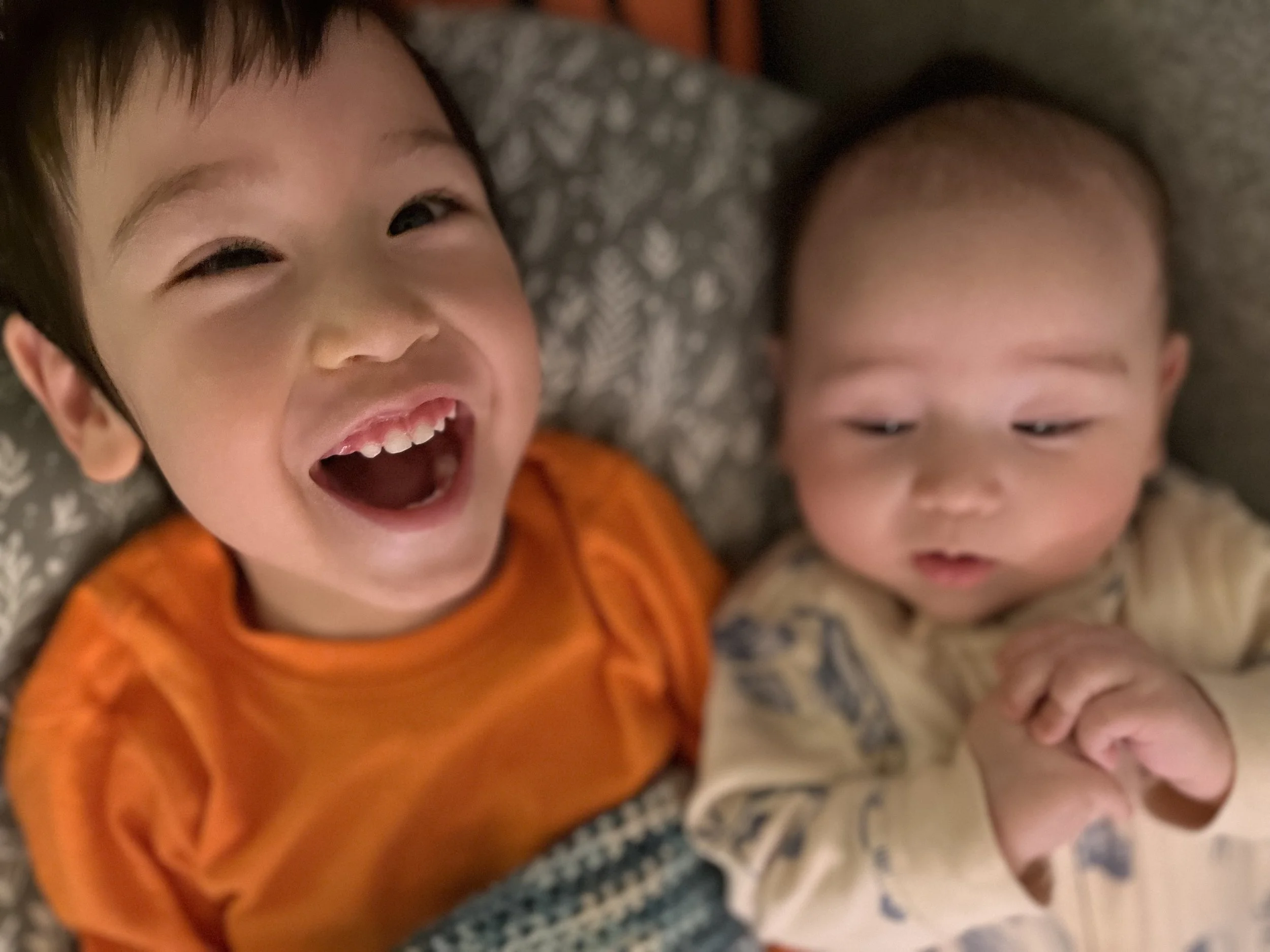 A boy stands in his red mobility device, a stander. A bright happy smile on his face.