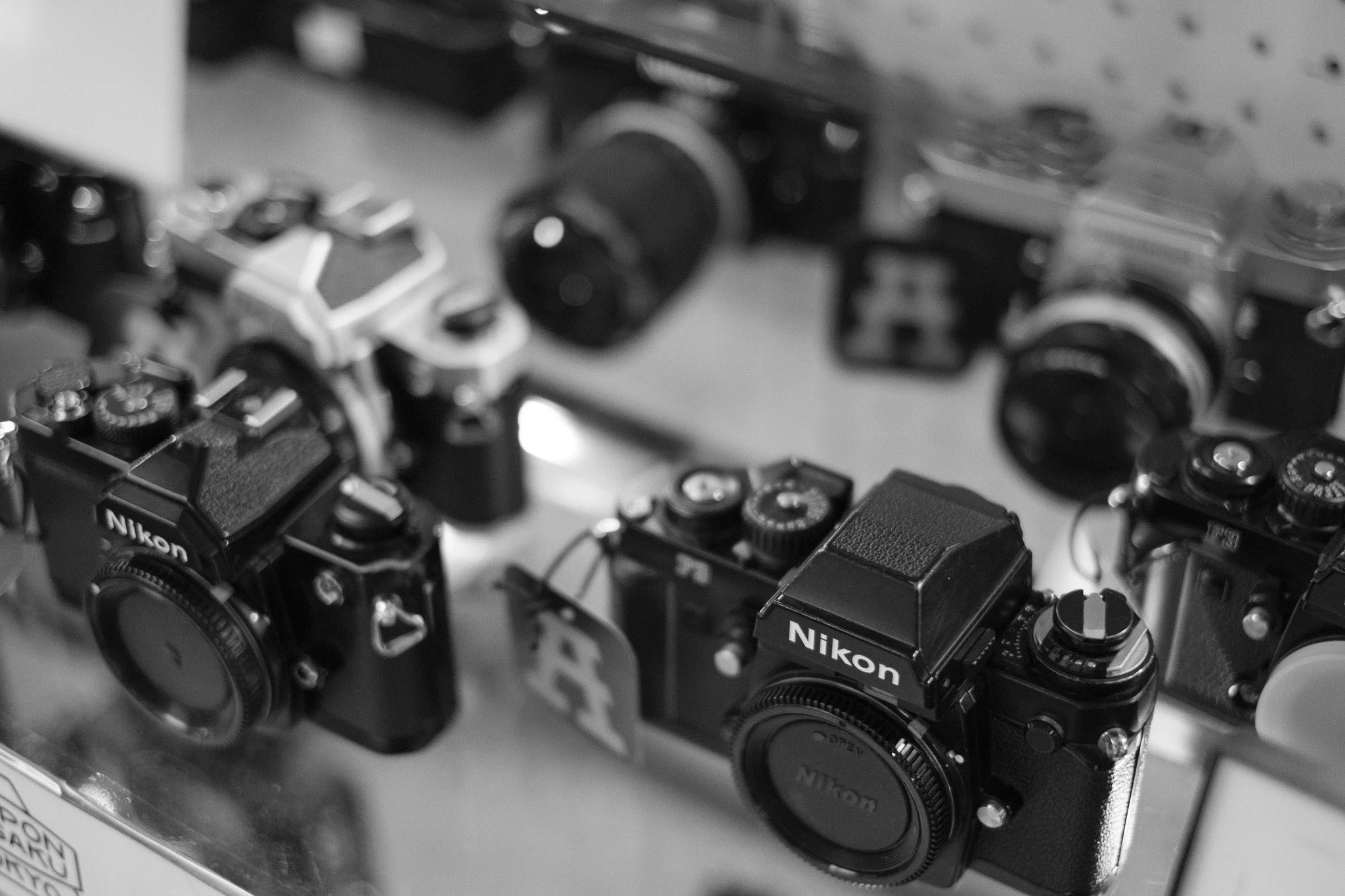 A display of vintage Nikon cameras in a store, arranged on a glass shelf.