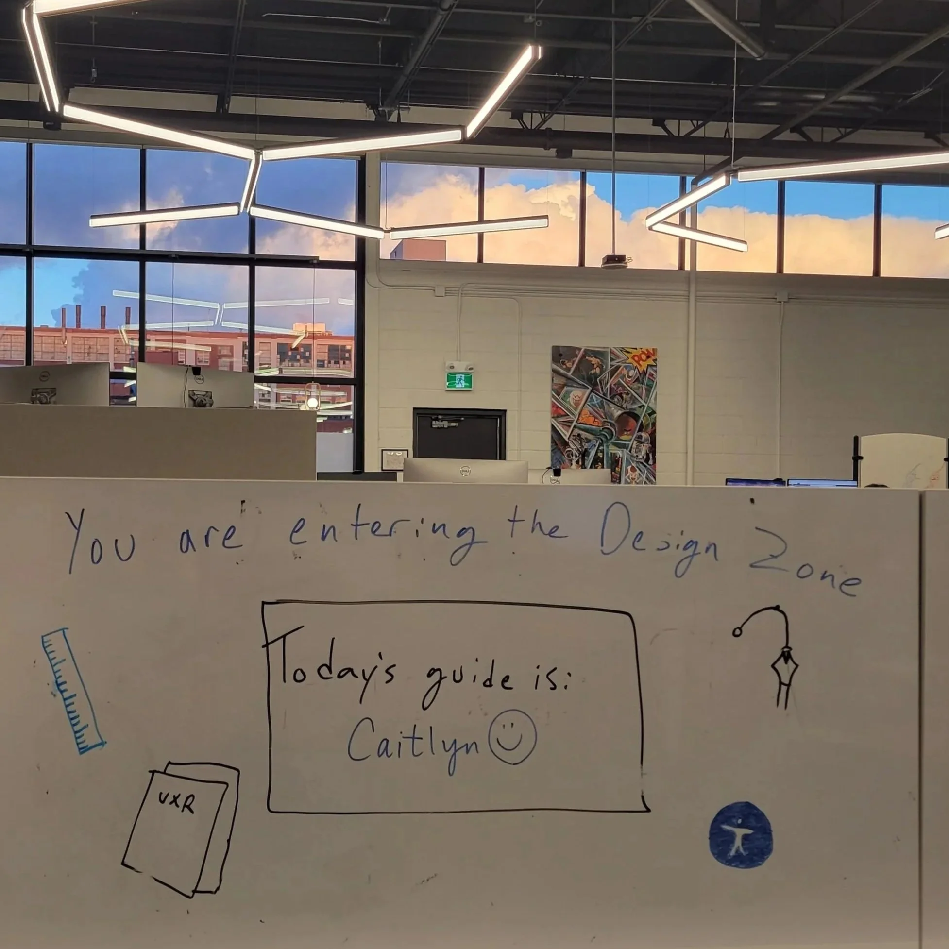 Whiteboard in the office that says "You are entering the Design Zone. Today's guide is: Caitlyn."