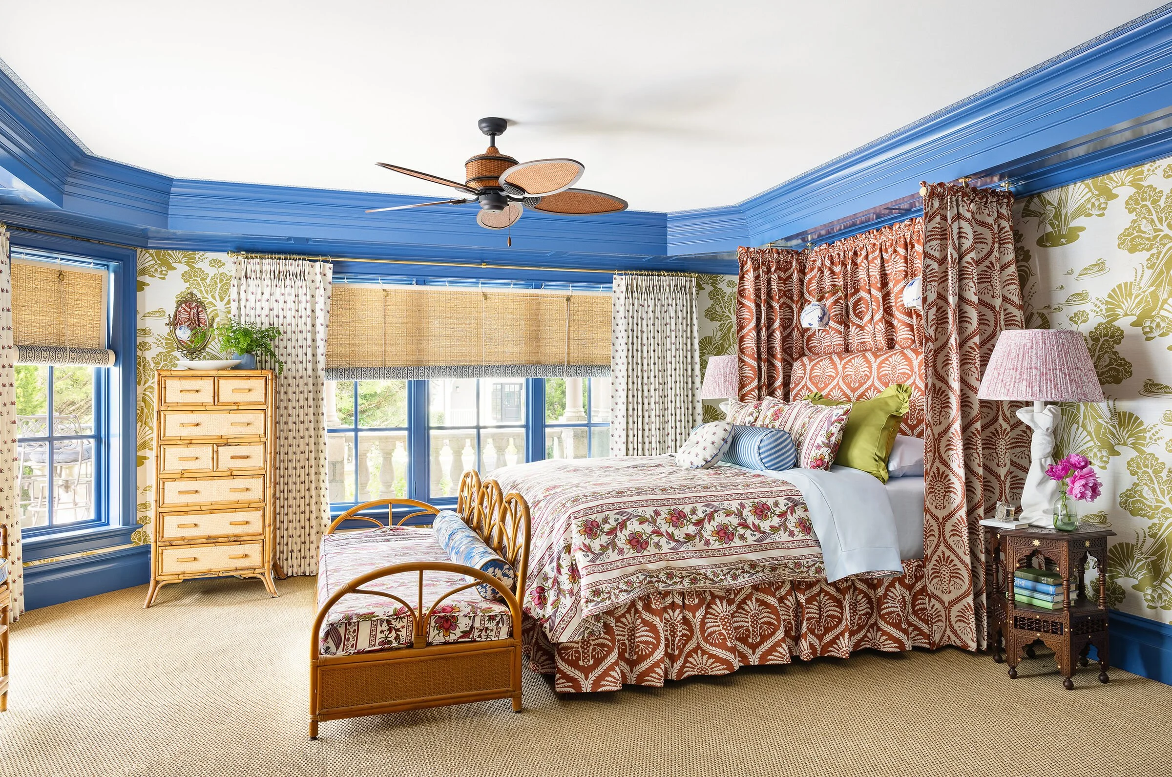 Primary bedroom with blue trim, a floral canopy bed and bamboo shades by Tartan and Toile Interior Design