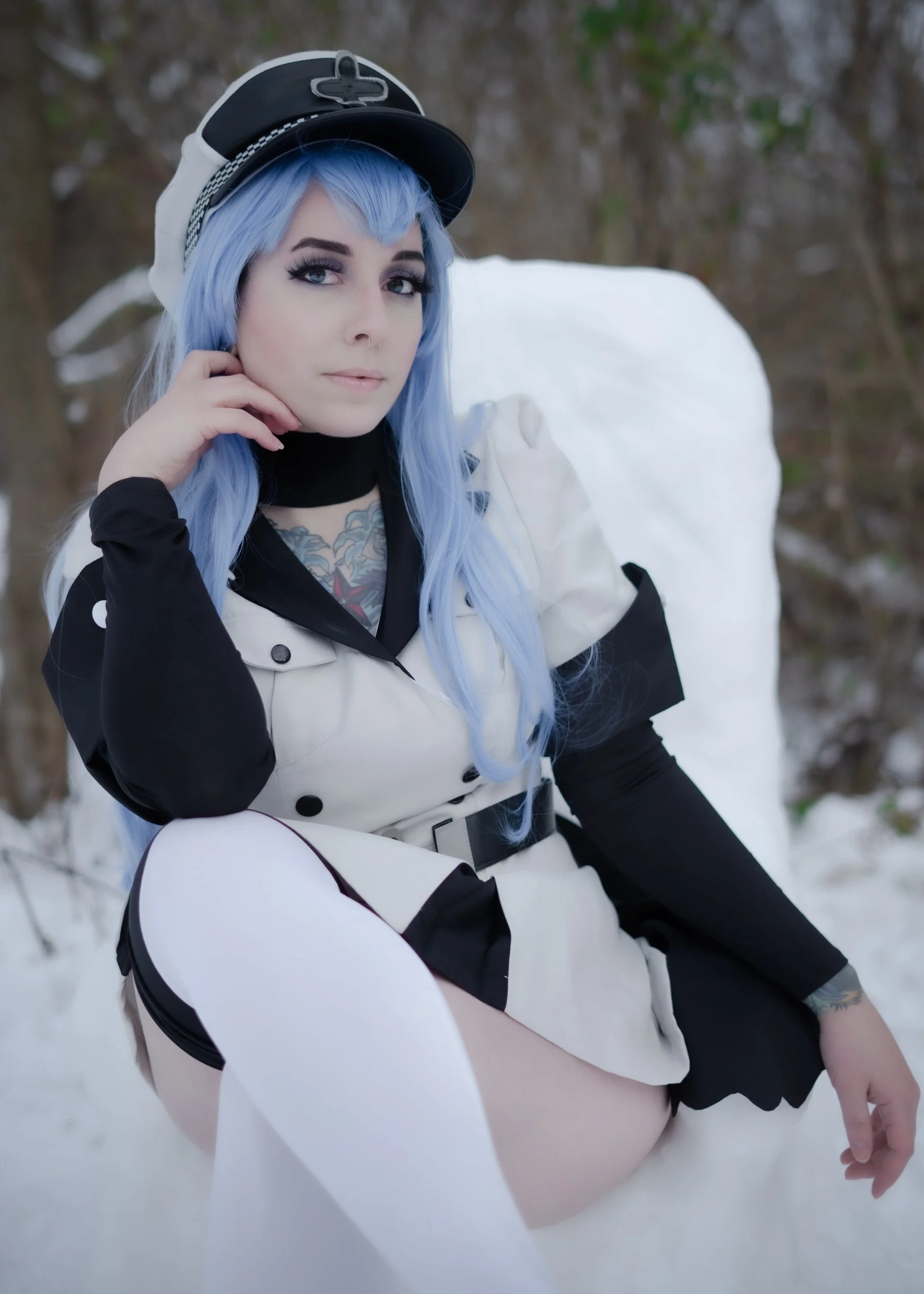 A woman with long blue hair, wearing a nurse uniform and a nurse hat, sits on snow-covered ground with a snowy background.