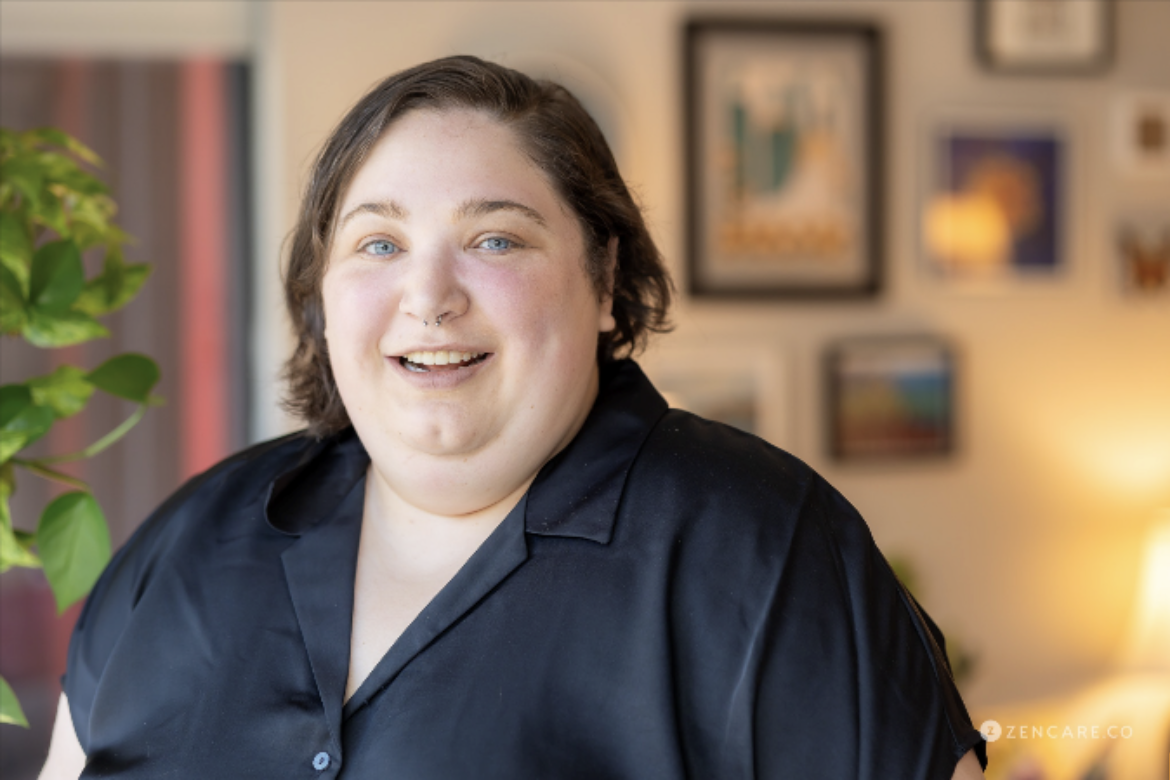 White Person with short brown hair wearing a black collared shirt and smiling.