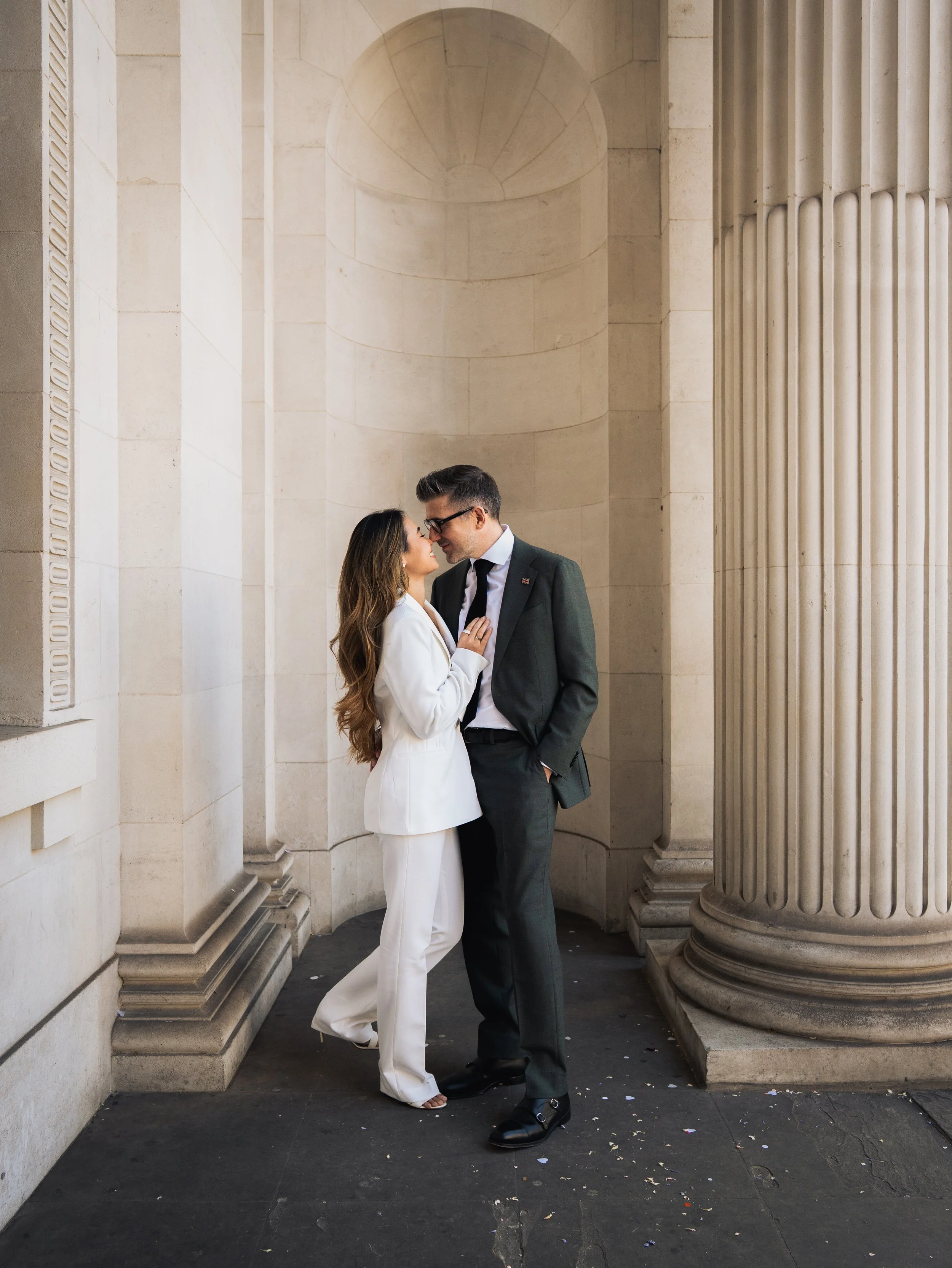 Couple embracing in a narrow outdoor alleyway with concrete walls and a wooden floor.