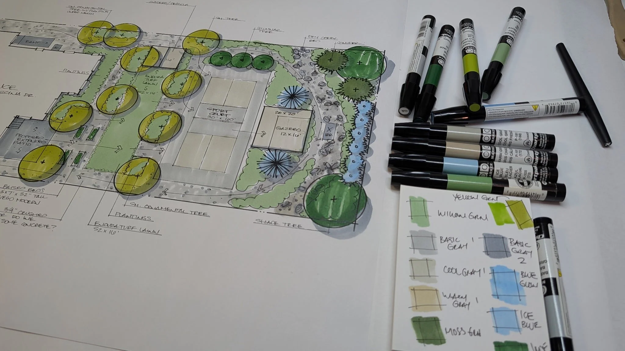 View of a hand-drawn landscape design plan, markers, and a color palette.