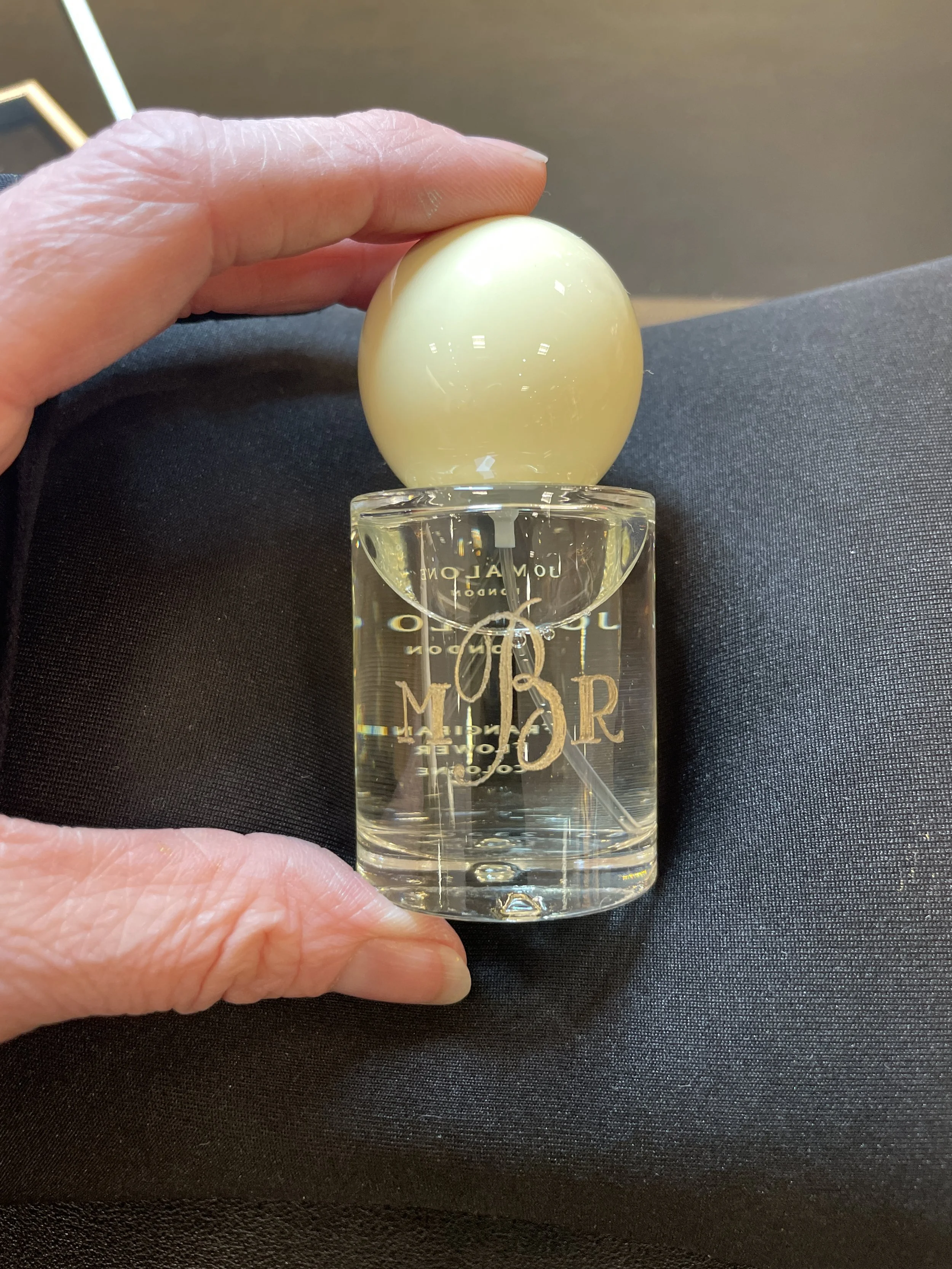 A hand holding a bottle of Jo Malone perfume with a large decorative egg on top.
