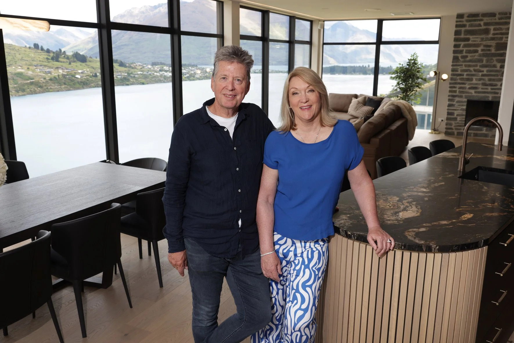 Two people posing in a modern living room with large windows overlooking a scenic lake and mountains. 
Co-ownership holiday homes
Luxury co-ownership properties
Fractional ownership real estate
Shared ownership holiday homes