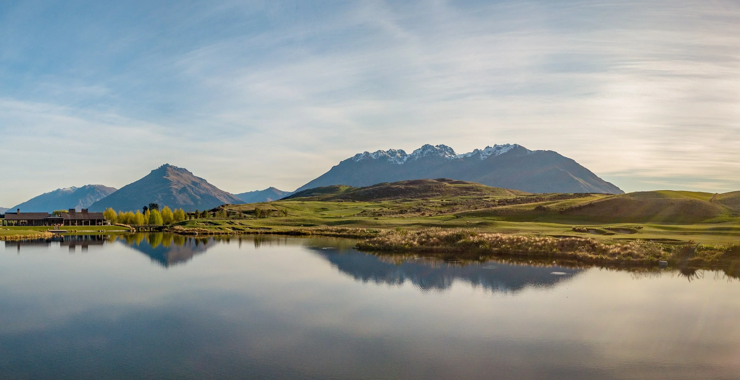 Scenic mountain landscape with a lake and grassy fields.