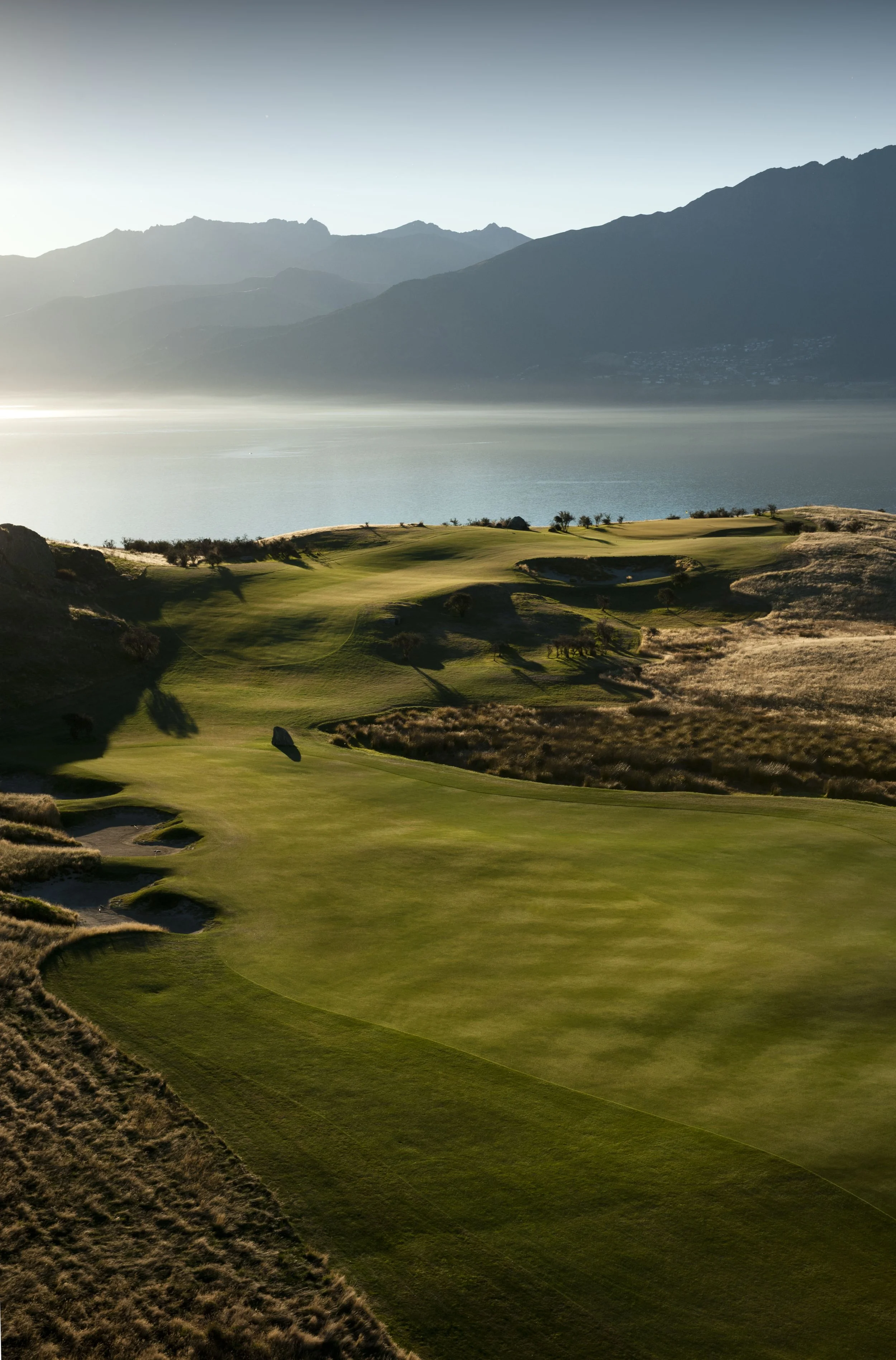 Scenic golf course with mountain and lake view at sunrise