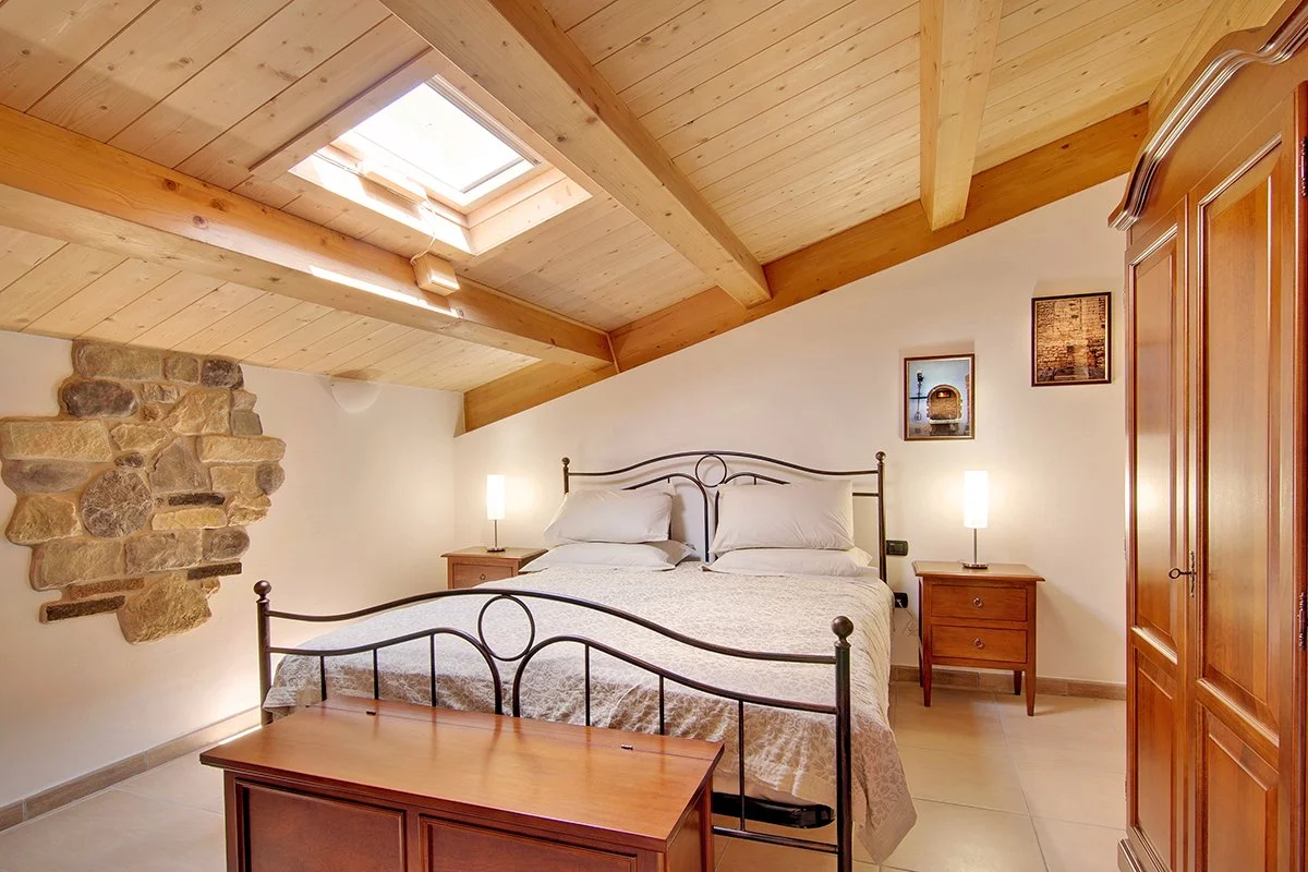 Cozy attic bedroom with wooden ceiling, double bed, and skylight