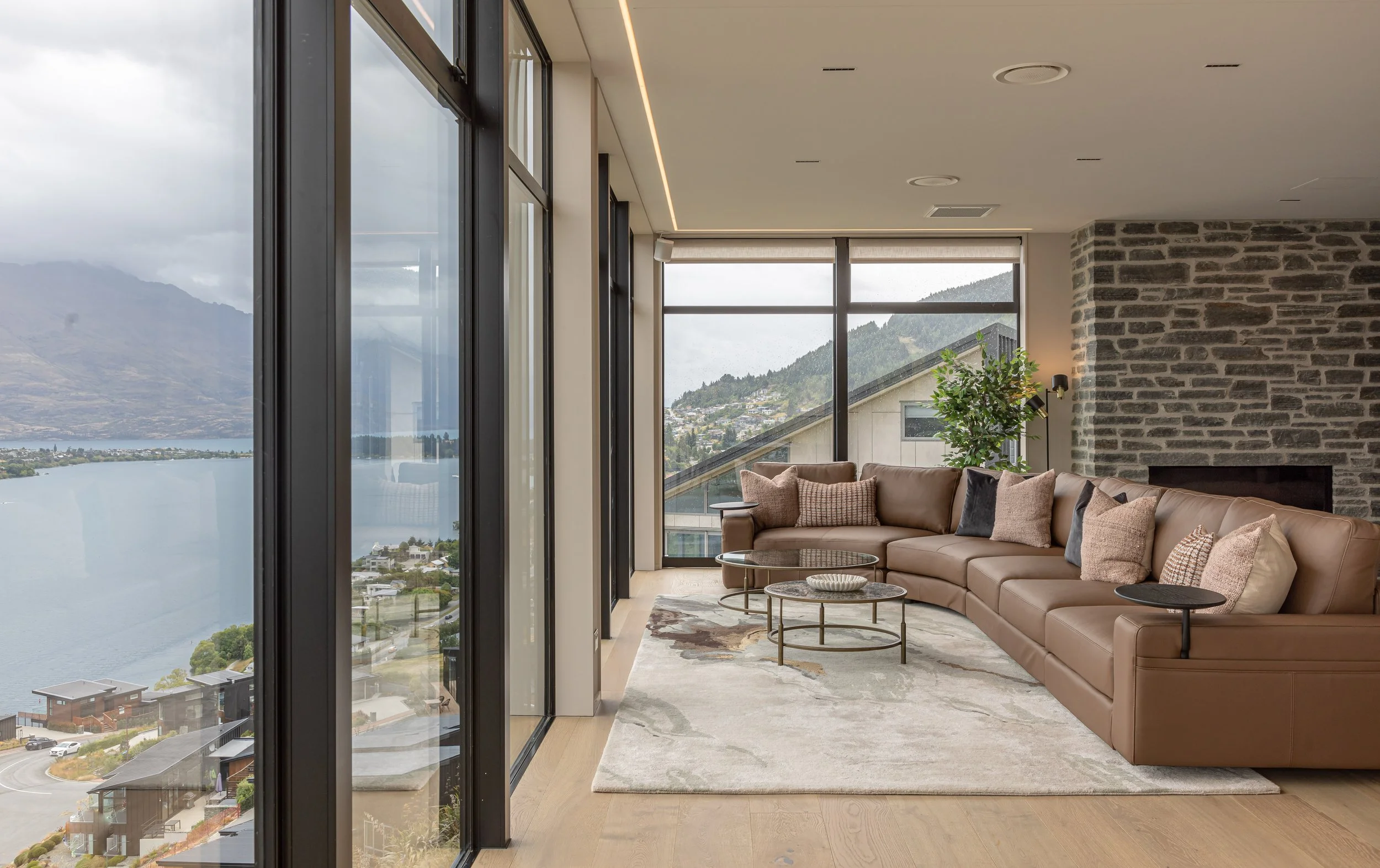 Modern living room with leather couch, large windows, and mountain view