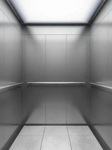 Empty modern elevator interior with metallic walls and ceiling lighting.