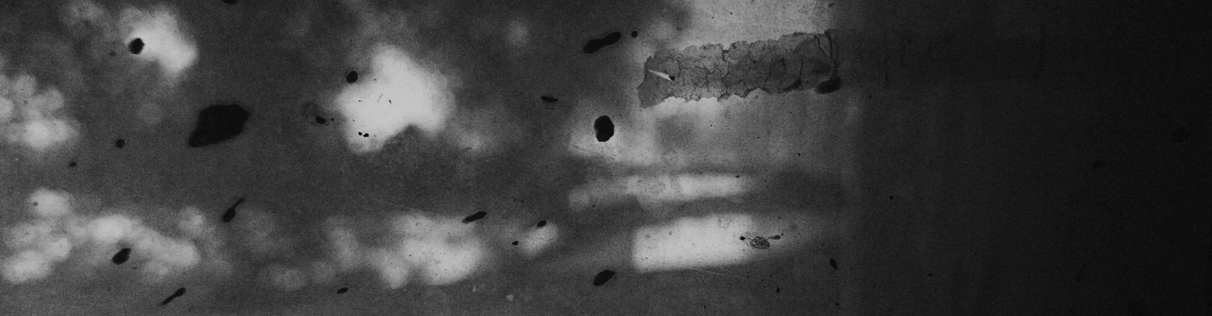 Close-up black and white photo of a bathroom mirror with smudges, dirt, and dust particles.