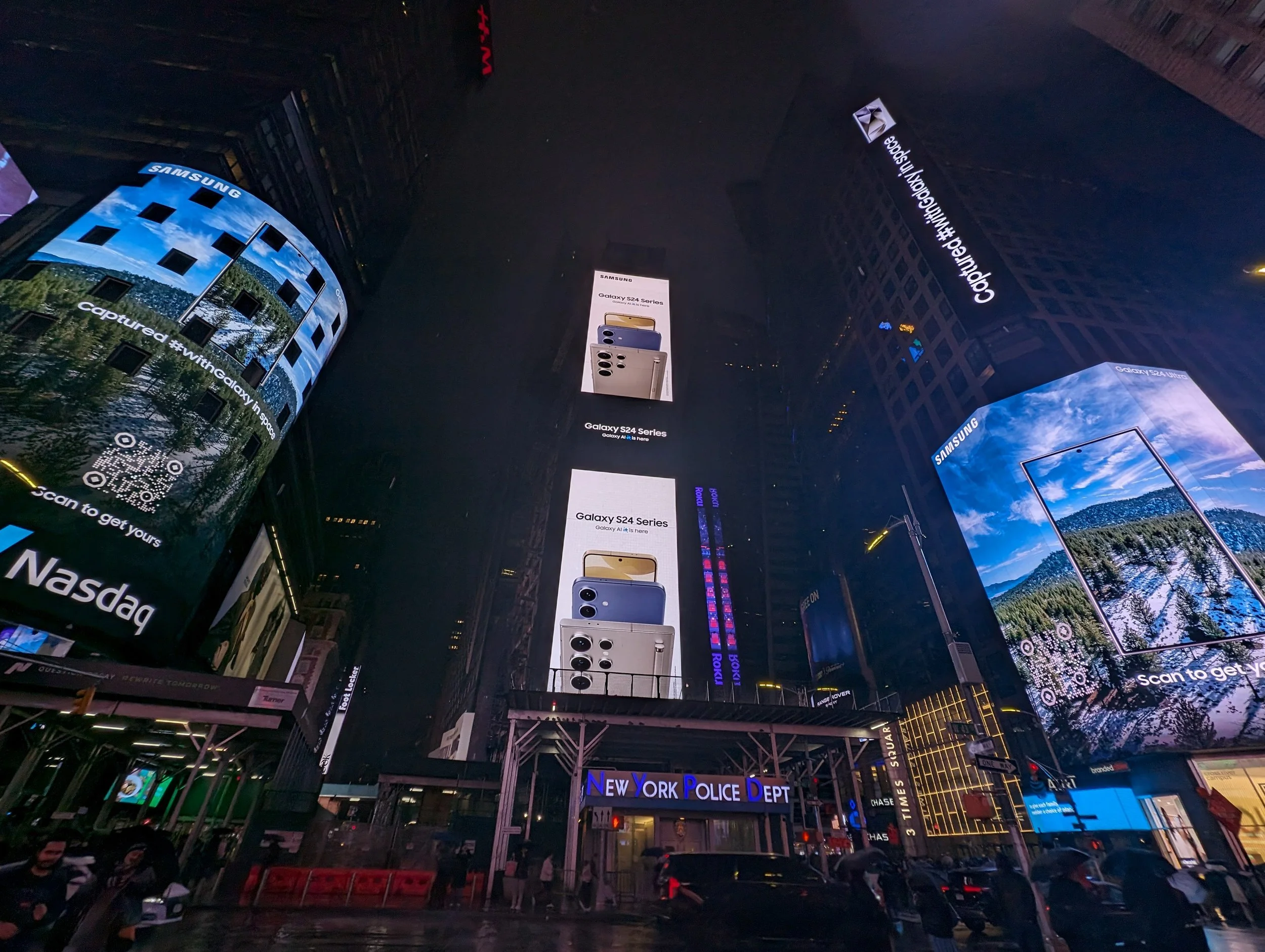 Times Square at night with Samsung and Nasdaq advertisements, New York Police Department, and illuminated billboards.