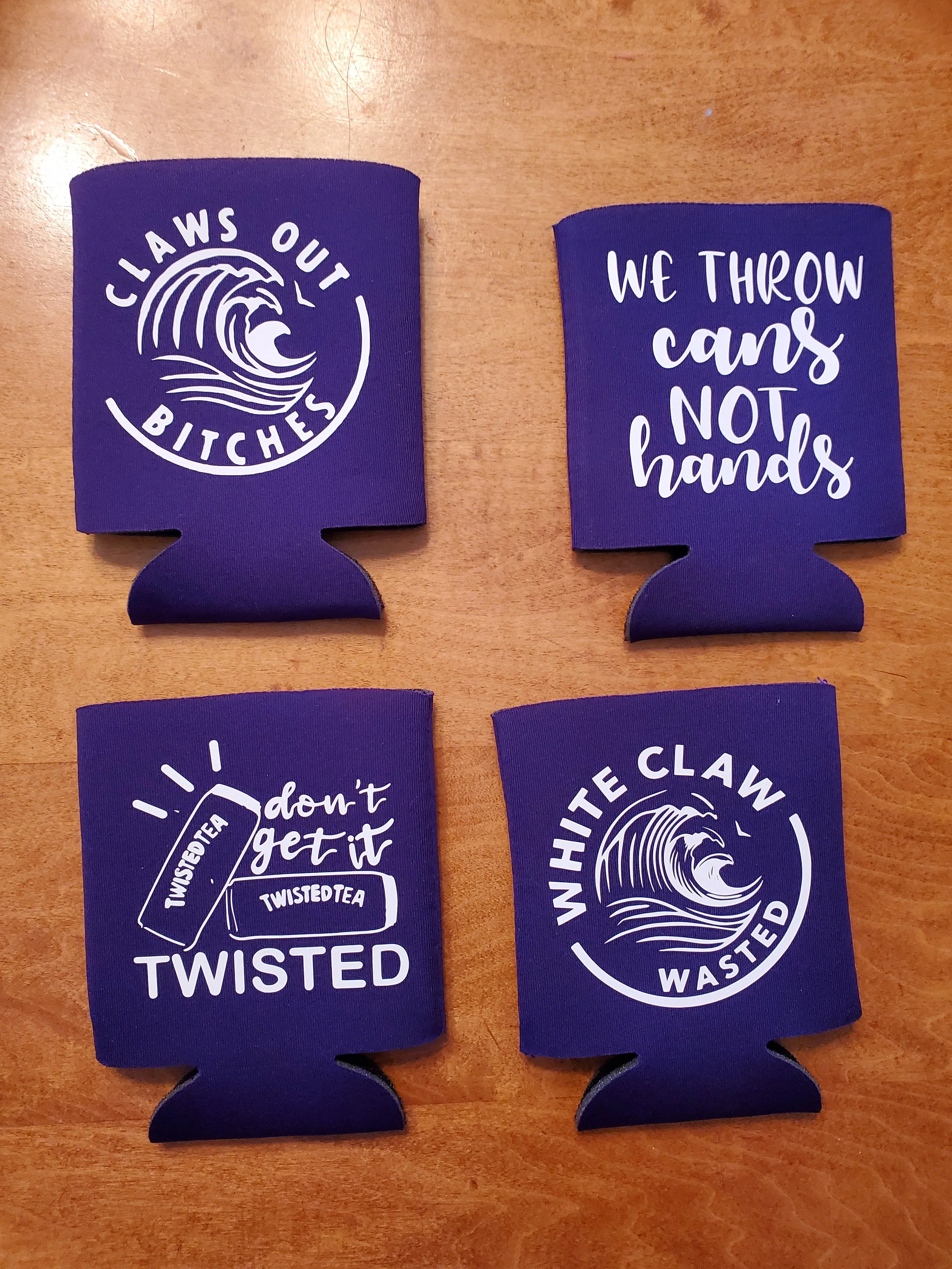 Four purple drink koozies with white text and graphics, two with waves and the phrases 'Claws Out Bitches' and 'White Claw Wasted', and two with the phrases 'We Throw Cans Not Hands' and 'Don't Get It Twisted' with a teabag graphic labeled 'Twisted T