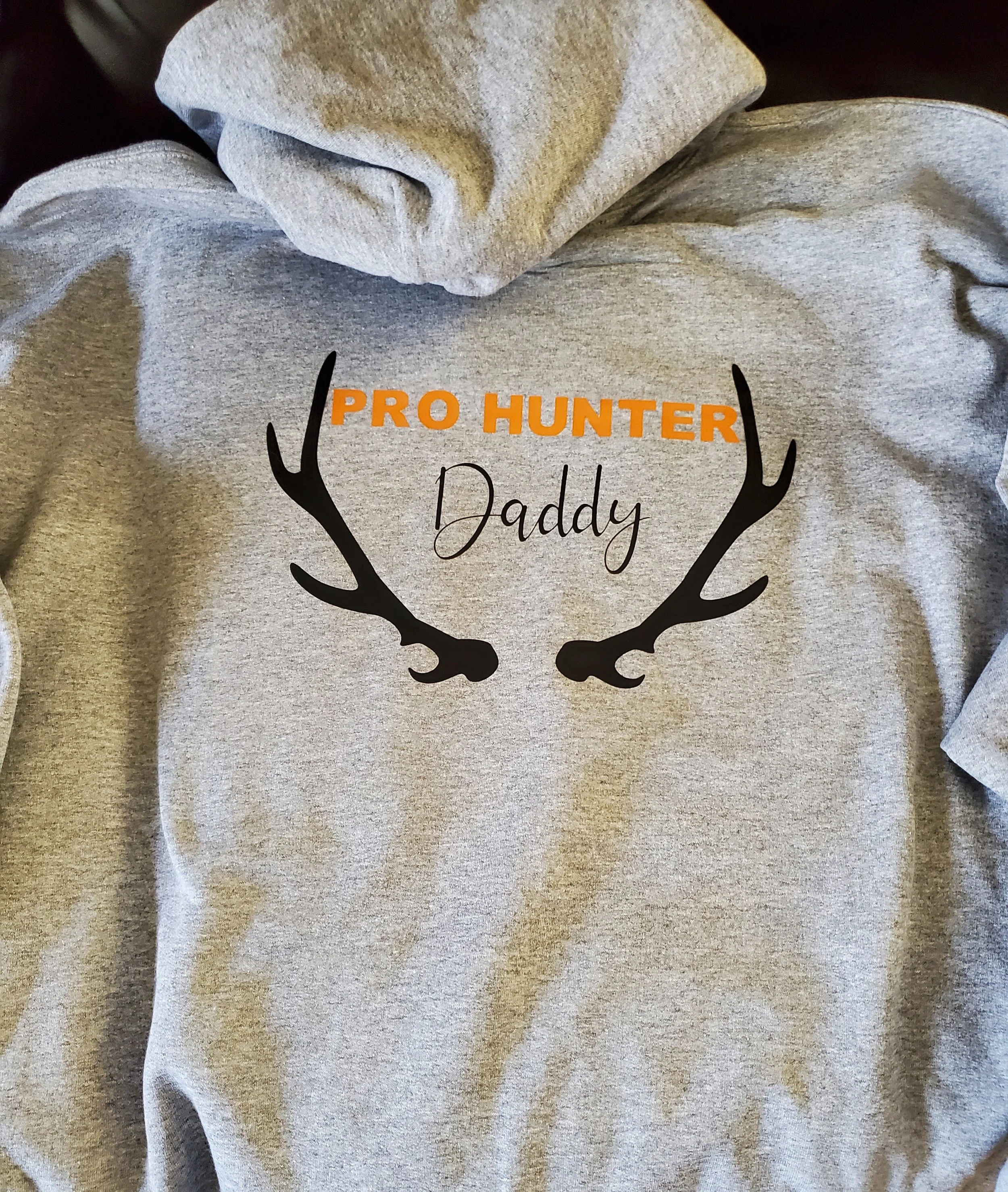 Gray hoodie with orange and black text that says 'Pro Hunter Daddy' and features a black silhouette of deer antlers.