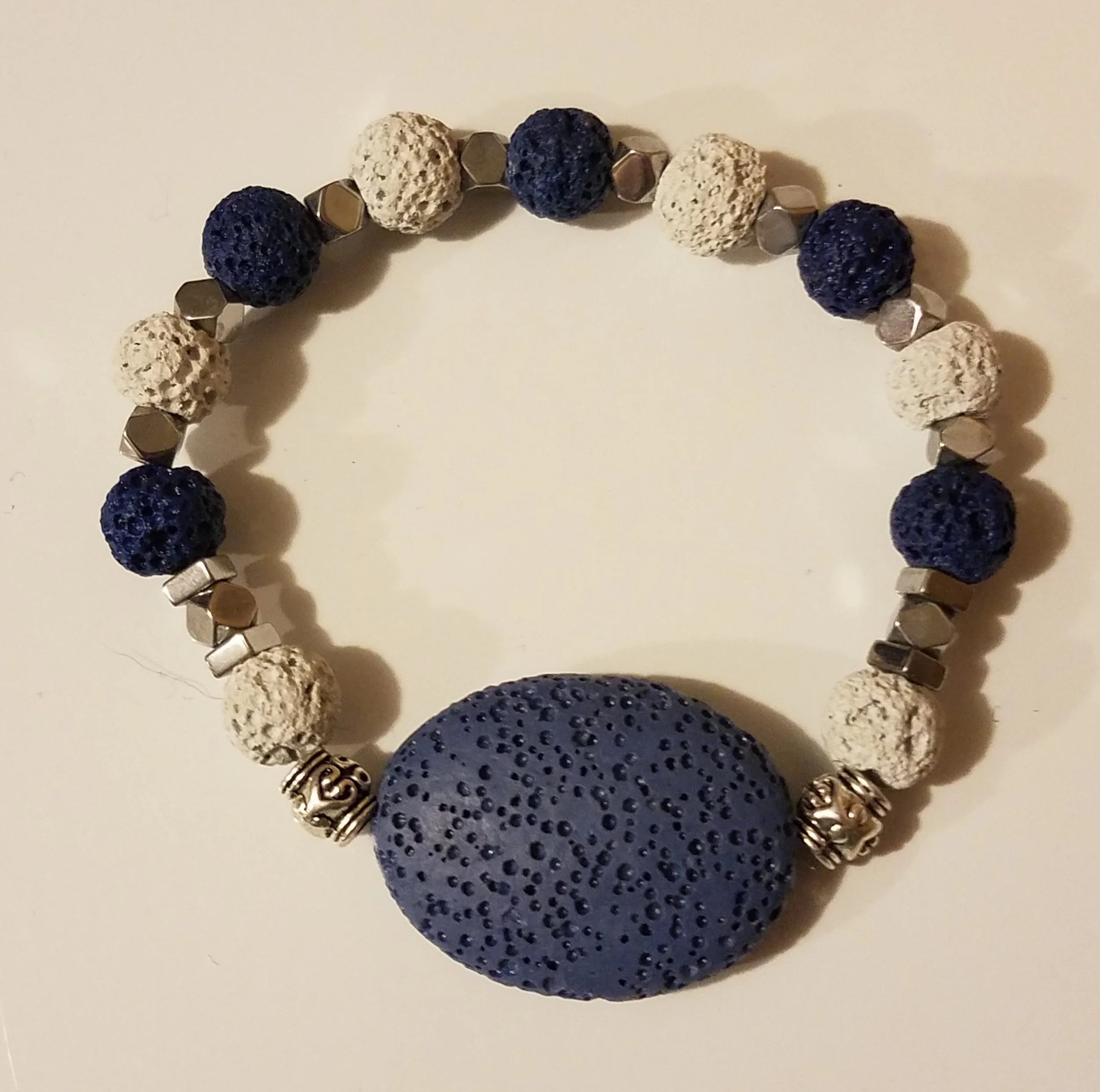 Necklace with large blue textured bead, white and navy smaller beads, silver geometric beads, and decorative silver spacers.