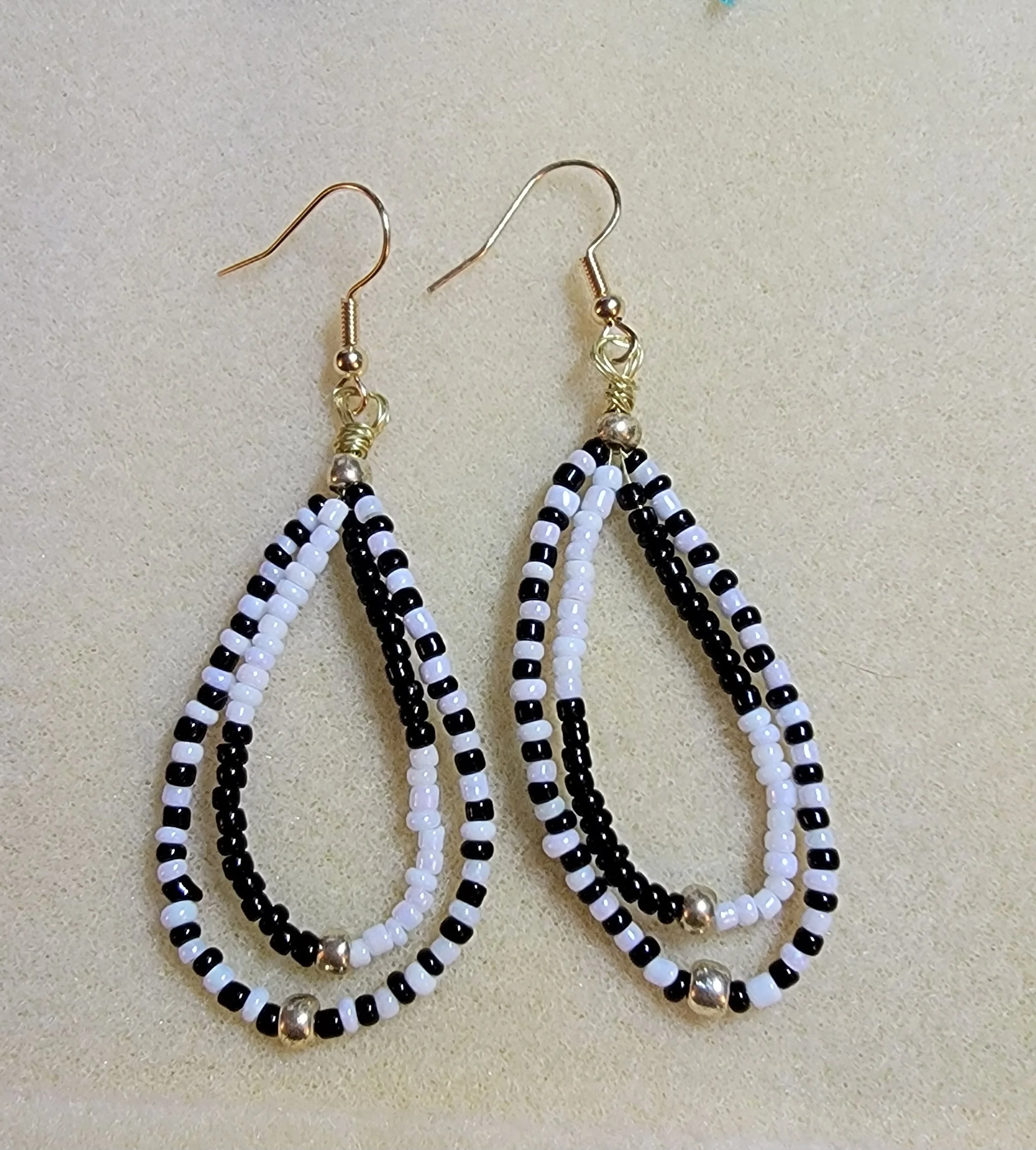 Black and white beaded teardrop earrings with small golden beads at the bottom.