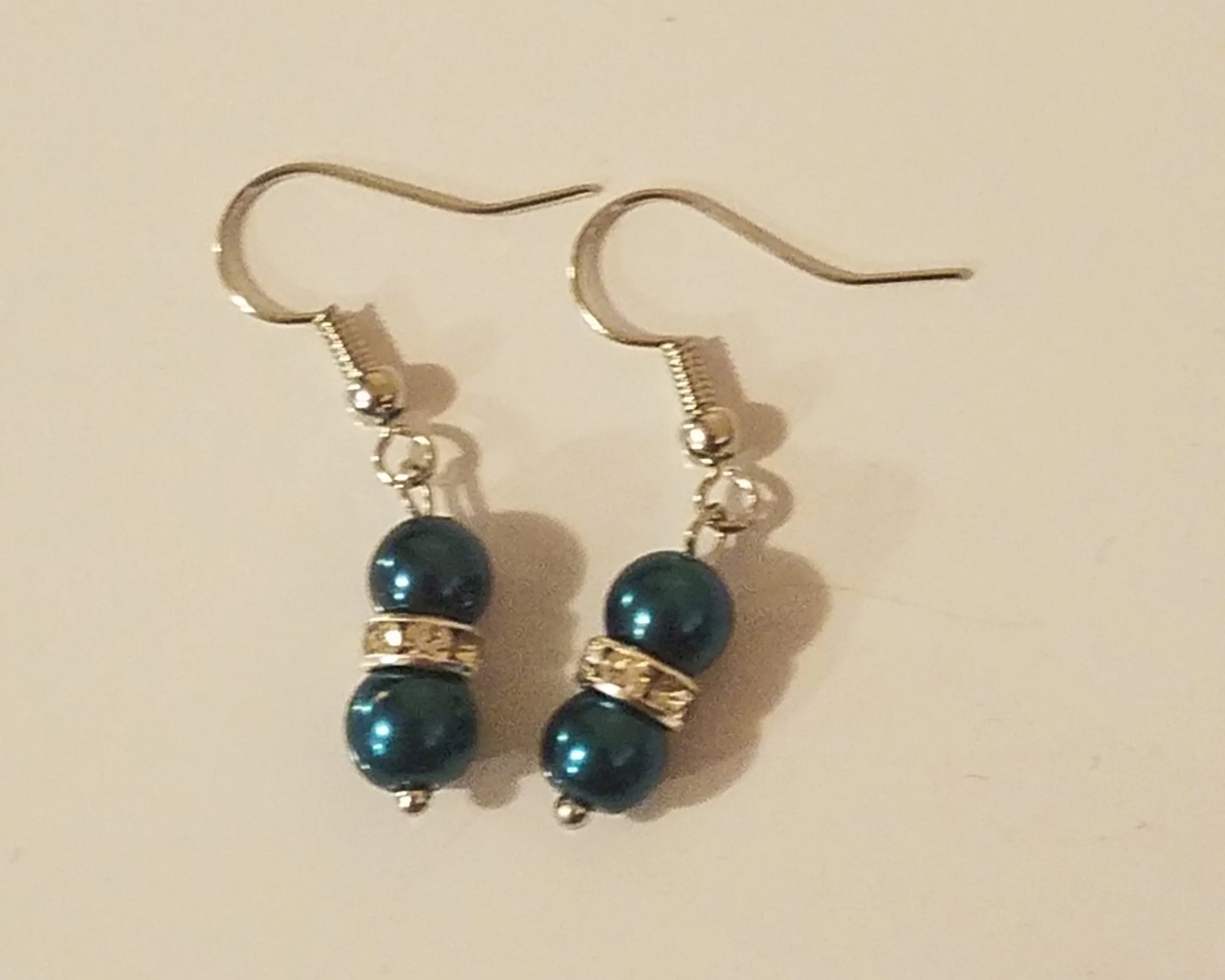 Silver hook earrings with three dark teal beads and small gold accents