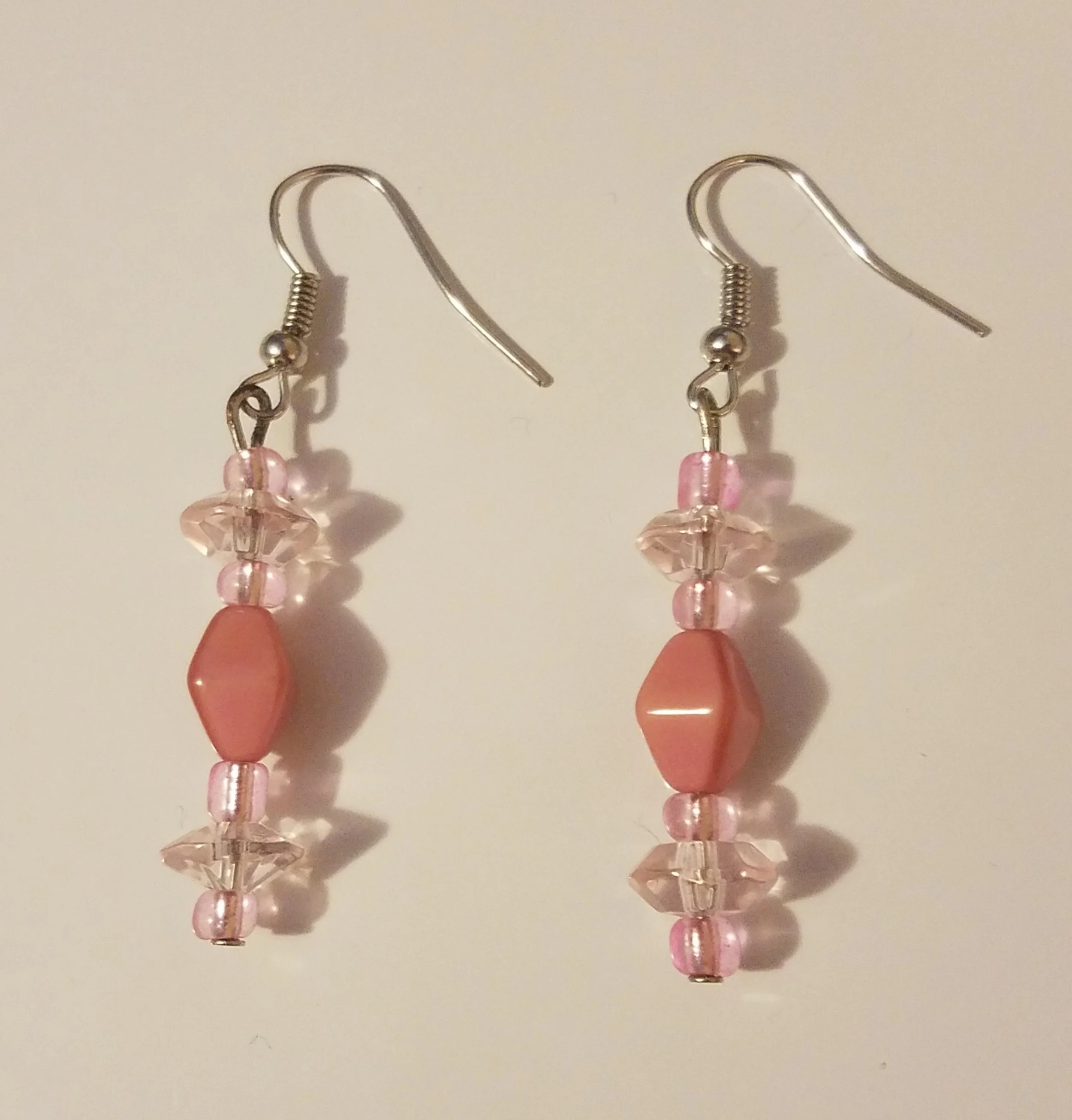 Pink bead earrings with a mix of opaque and transparent beads hanging from metal hooks.
